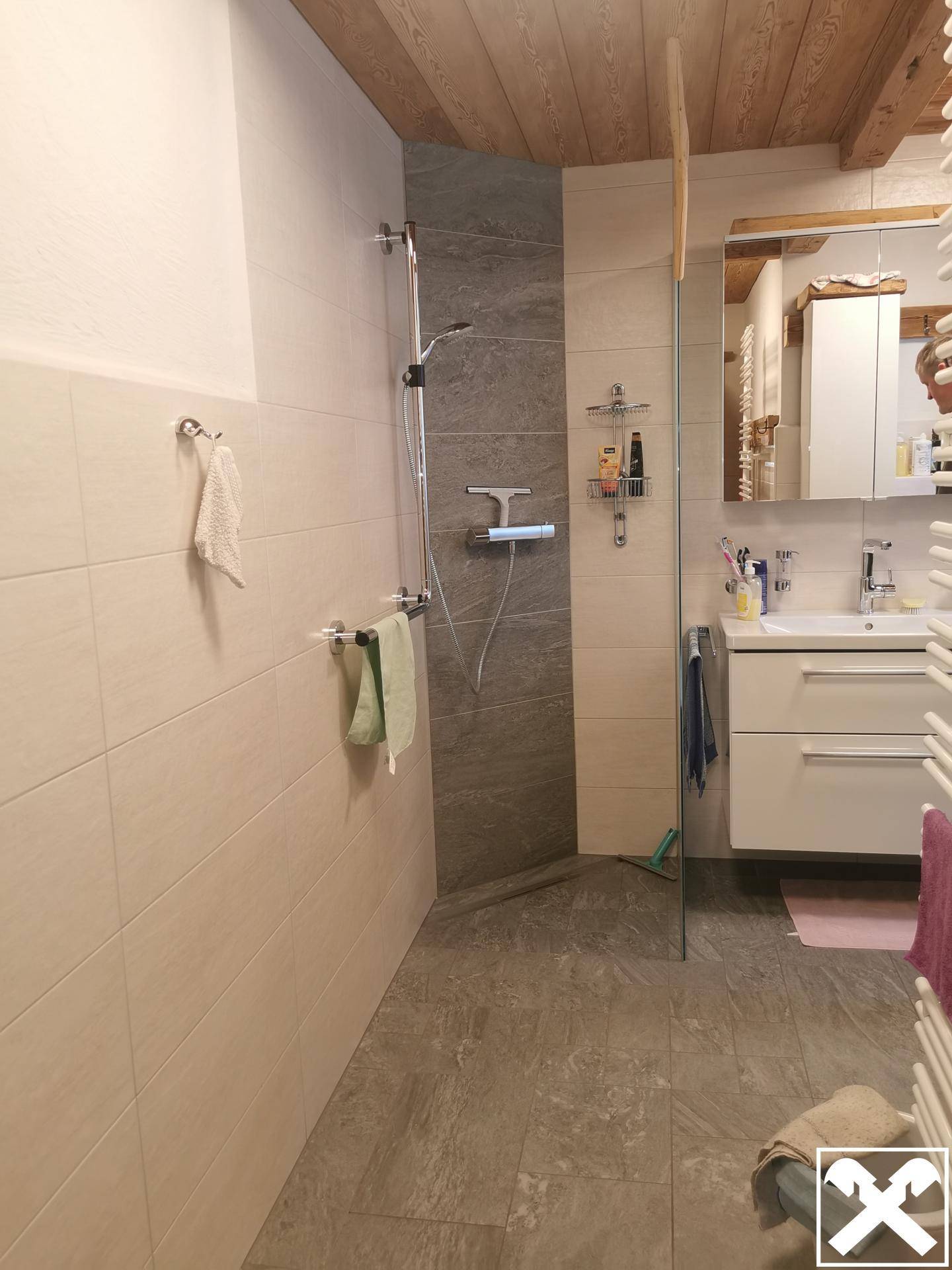 Modernes Badezimmer mit begehbarer Dusche, hellen Fliesen und einem beheizten Handtuchhalter.