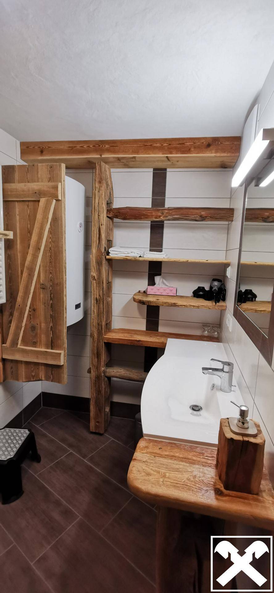 Badezimmer mit modernem Waschbecken, Spiegelschrank und rustikalen Holzregalen für Stauraum.