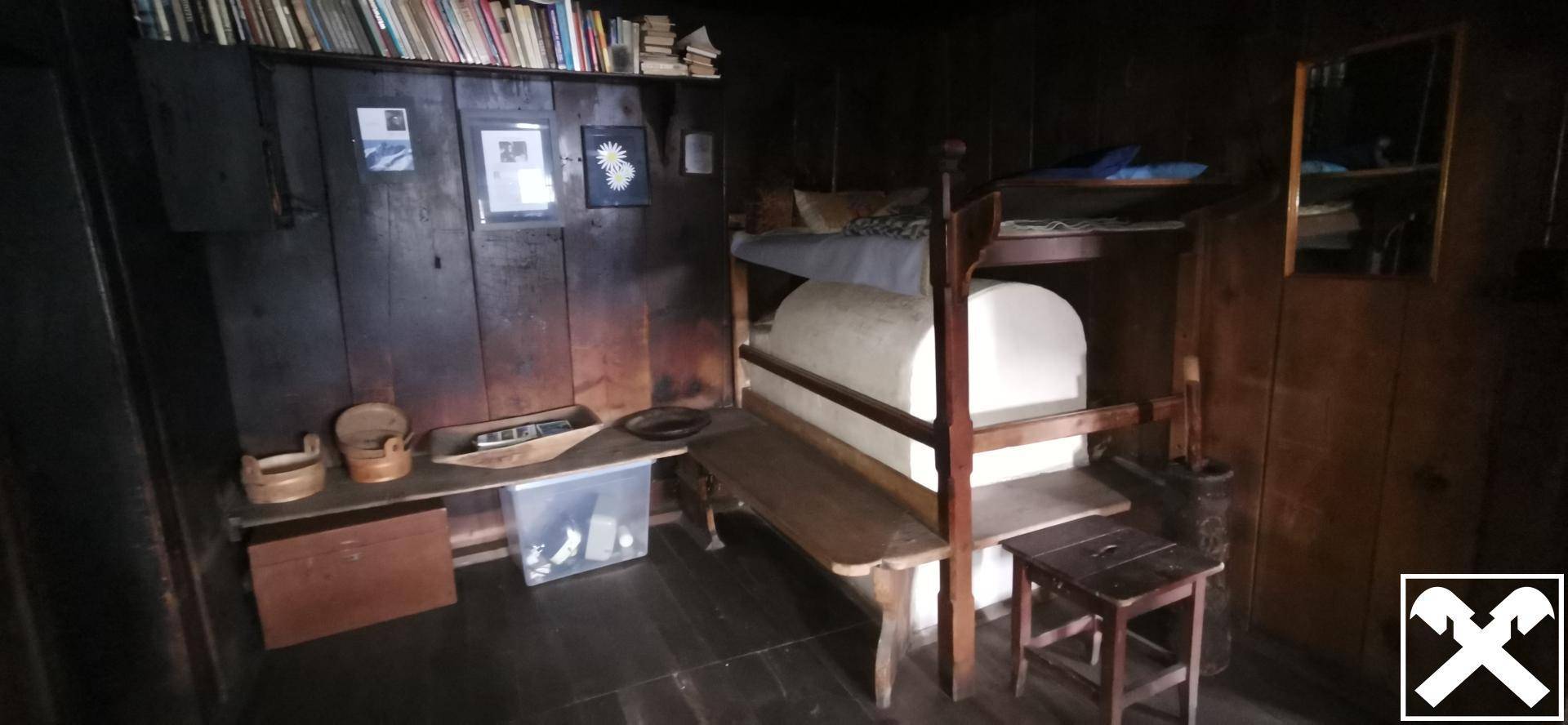 Dunkles, rustikales Schlafzimmer mit Holzwänden, Etagenbett und einfacher, traditioneller Einrichtung.