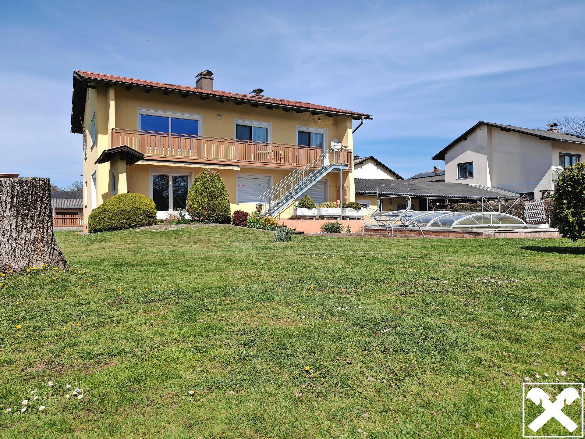 Weitläufiger Garten mit großer Rasenfläche, Baumbestand und Blick auf das Haus mit Pool.