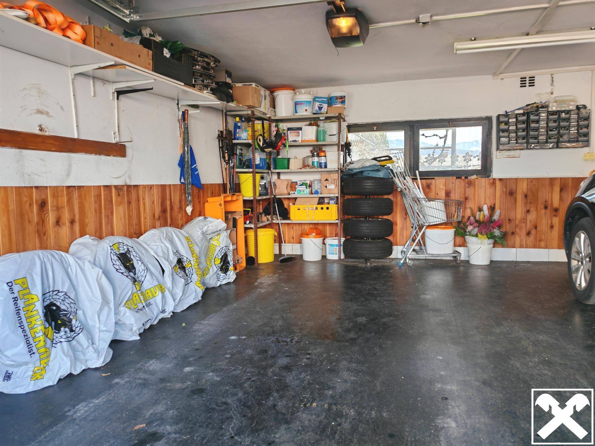 Geräumige Garage mit Stauraum, Regalen und Holzvertäfelung an den Wänden.