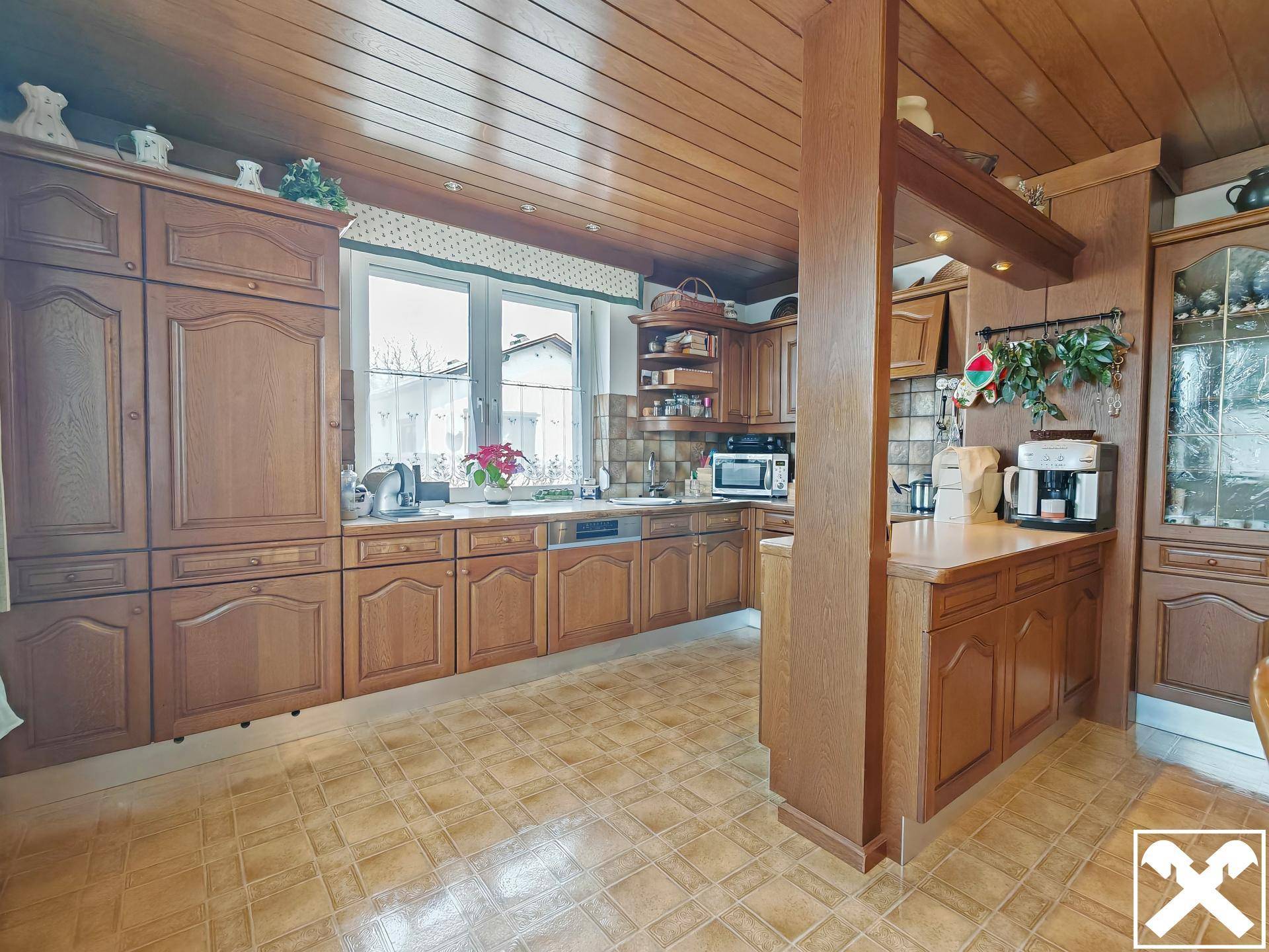 Traditionelle Holzküche mit Einbaugeräten, viel Stauraum und Fenster.