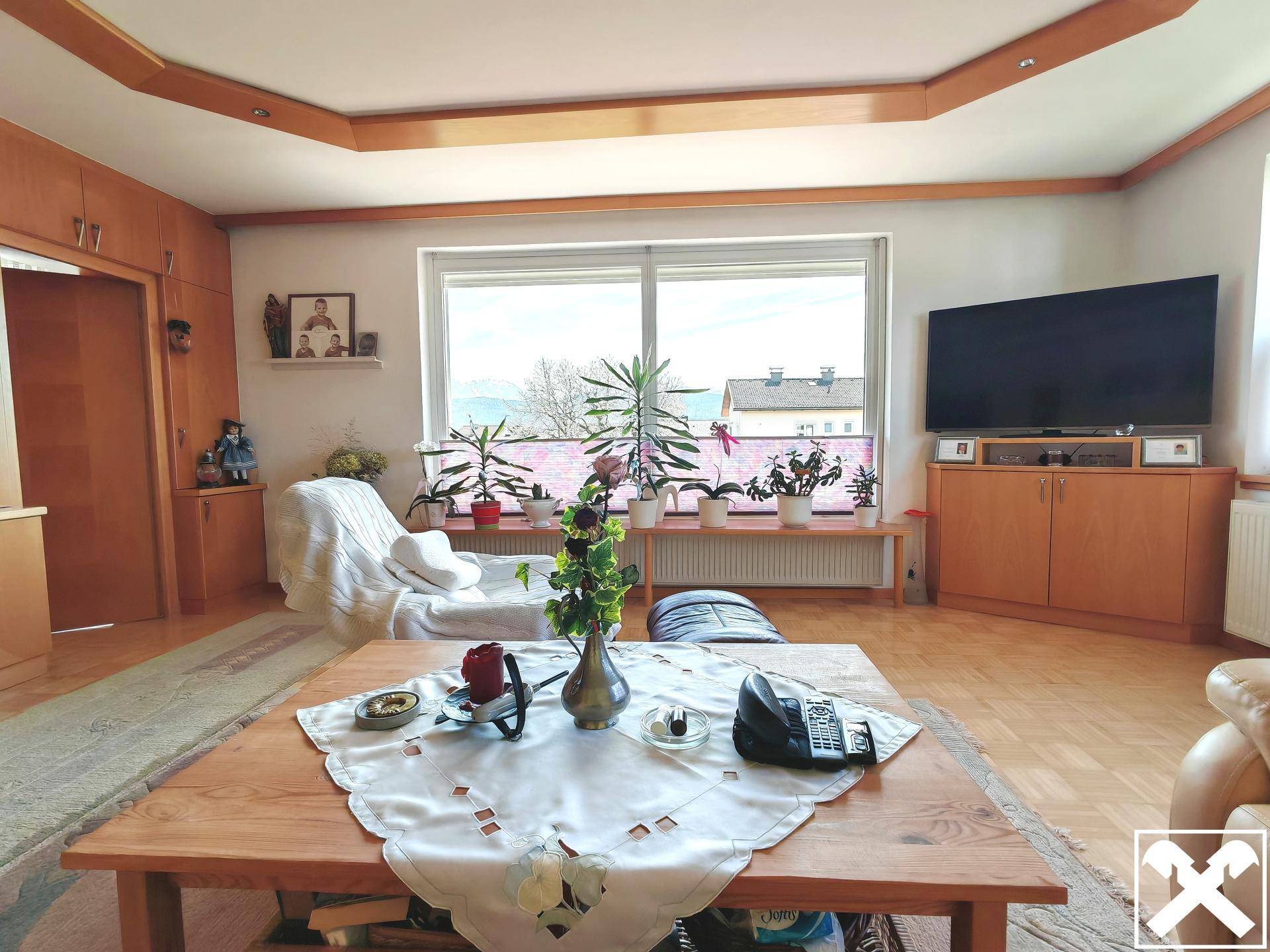 Gemütliches Wohnzimmer mit Holzboden, großem Fenster und Blick auf die Umgebung.