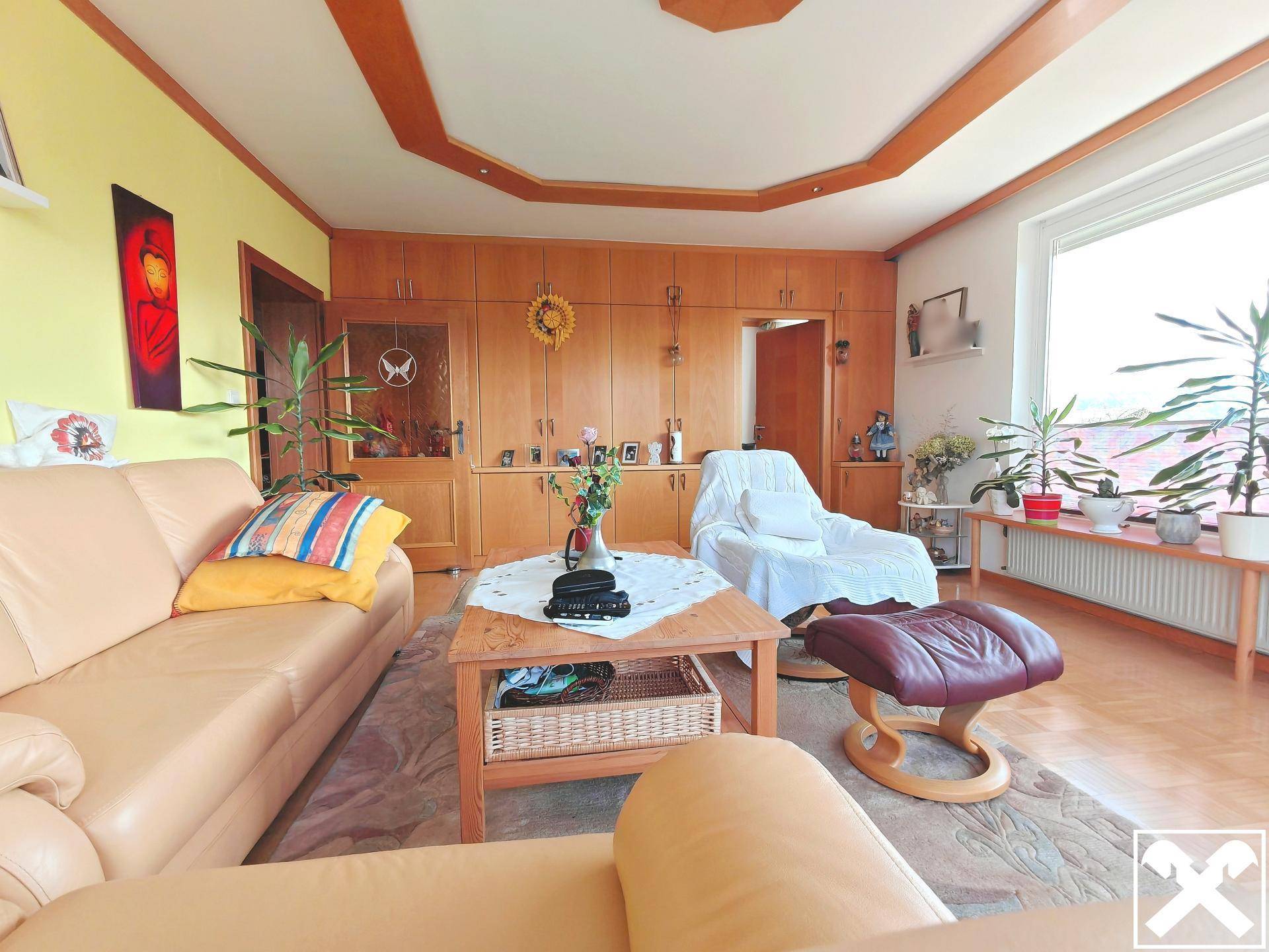 Wohnzimmer mit beiger Ledercouch, Holzeinbauschränken und dekorativer Decke.