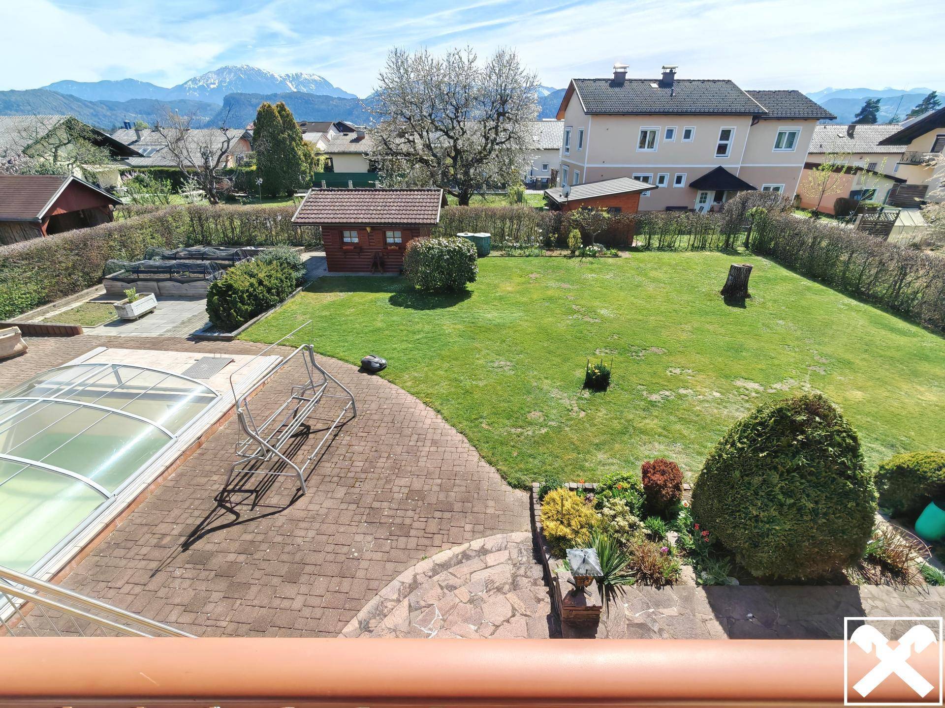 Weitläufiger Garten mit Rasenfläche und Poolbereich vor beeindruckender Bergkulisse.