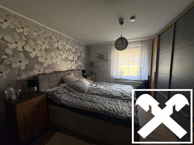 Schlafzimmer mit floraler Tapete, Doppelbett und großem Kleiderschrank.