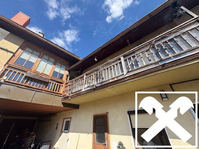 Alter Holz-Balkon mit traditionellem Geländer und Blick auf den Himmel.