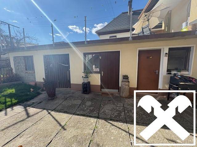 Gepflasterter Terrassenbereich mit Nebengebäude und Sitzgelegenheiten im Freien.