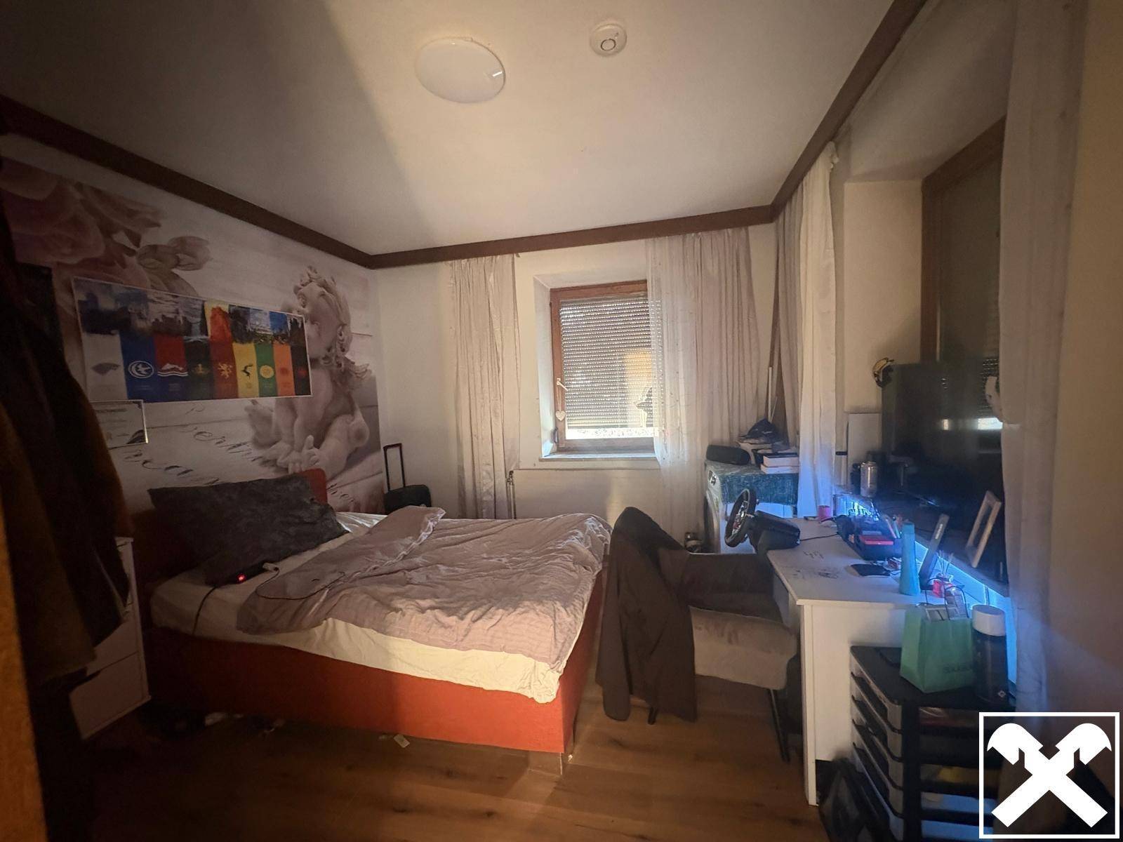 Gemütliches Schlafzimmer mit Holzboden, Doppelbett und dekorativer Wandgestaltung.