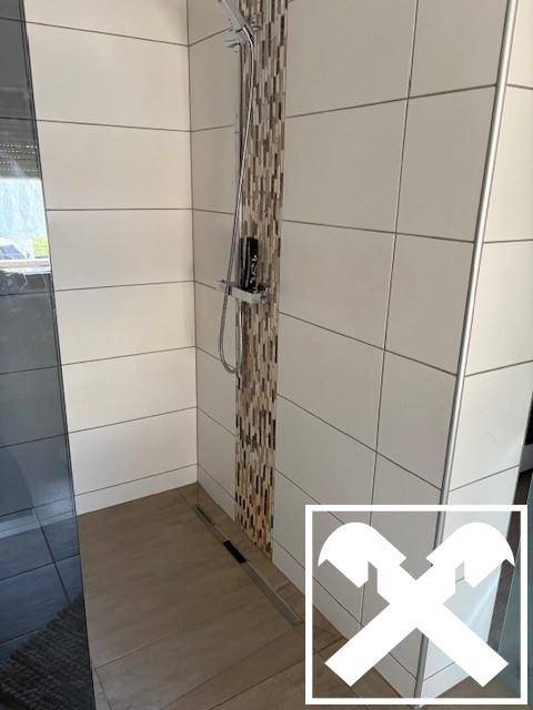 Moderne Duschkabine mit Fliesen in Weiß und Mosaikstreifen.