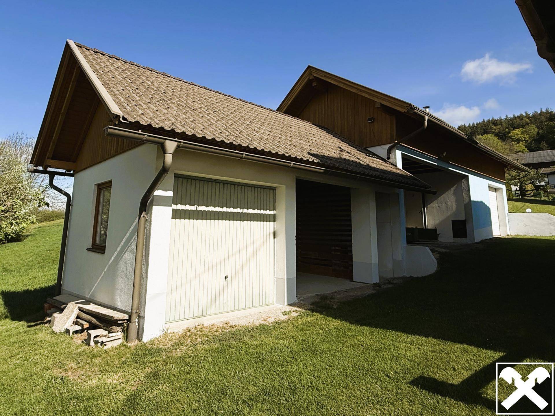 Nebengebäude mit Garage und Carport, umgeben von einer grünen Wiese.