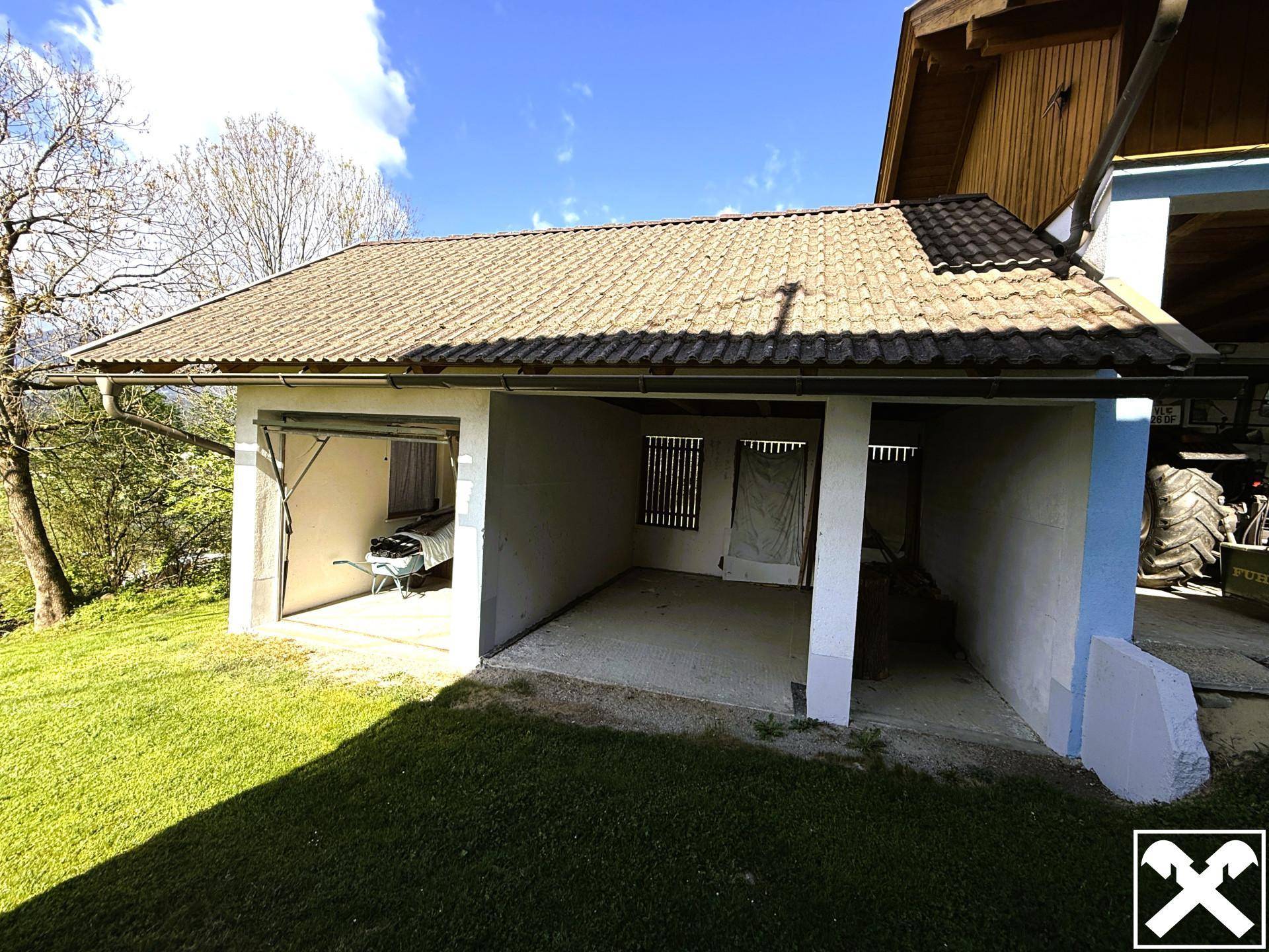 Offener Carport-Bereich mit angrenzender Garage und viel Platz im Freien.