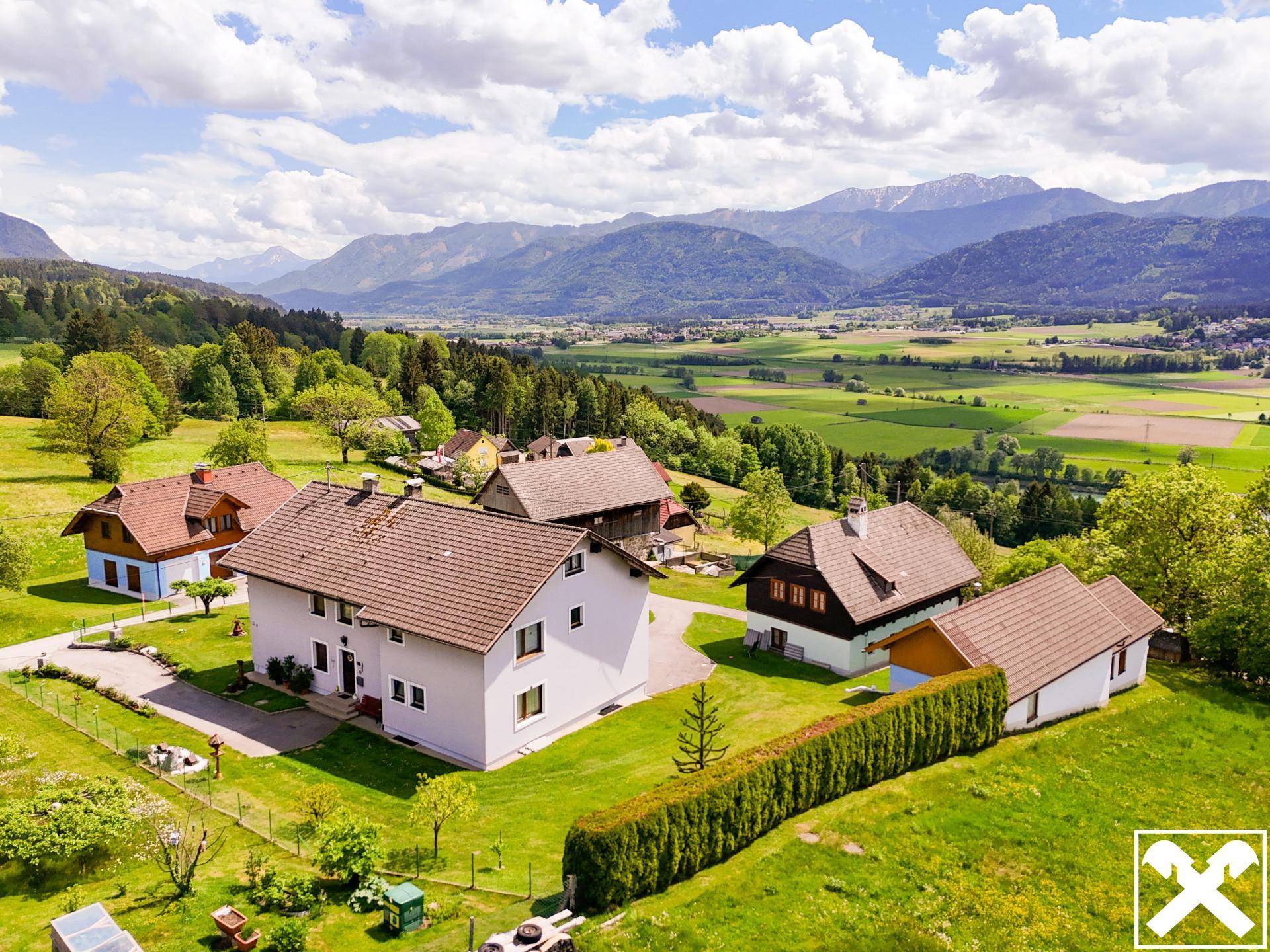 Luftaufnahme des Anwesens mit mehreren Gebäuden, großem Garten und Bergblick.