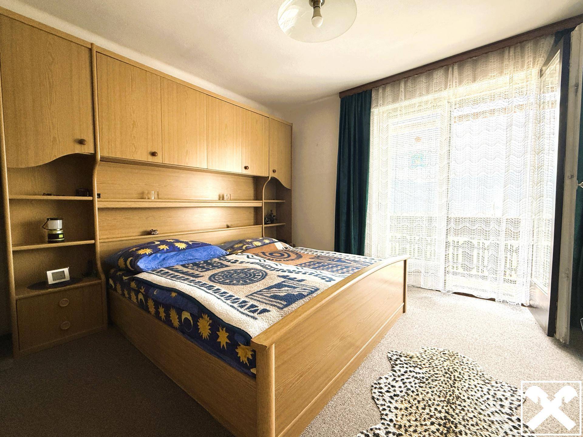Schlafzimmer mit Doppelbett, Einbauschränken und Zugang zu einem Balkon.