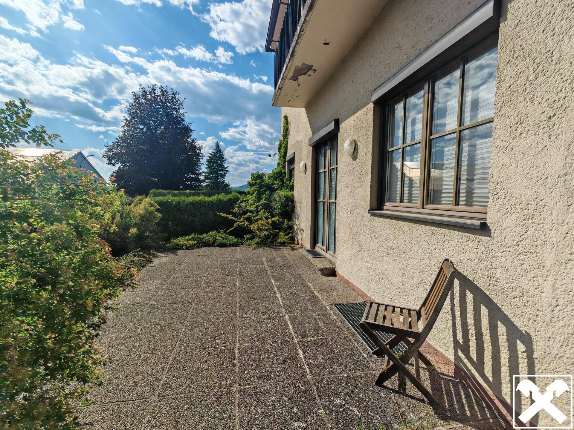 Kleine gepflasterte Terrasse am Haus mit Sitzgelegenheit und Blick in den Garten.