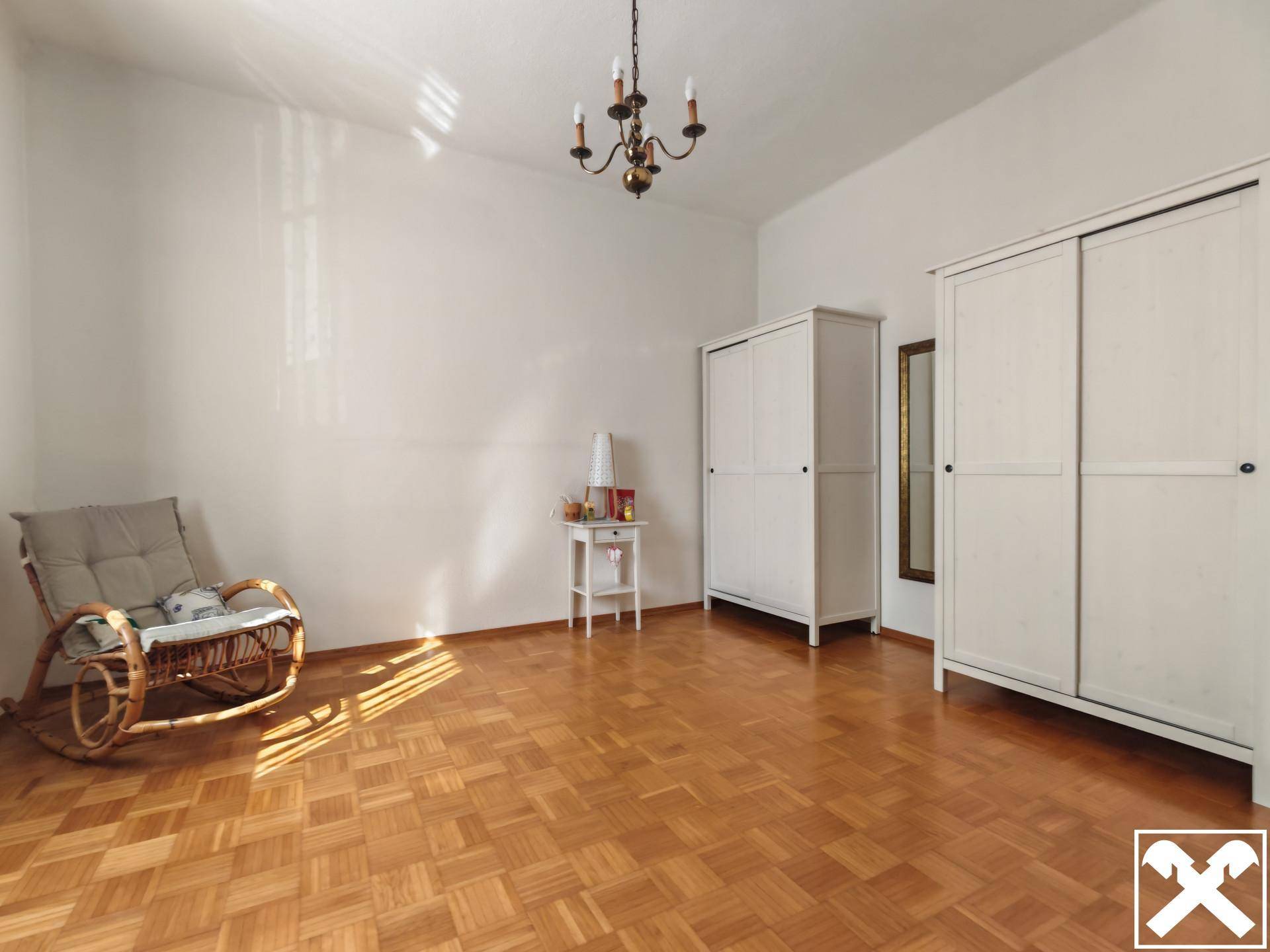 Geräumiges Schlafzimmer mit Parkettboden, zwei Kleiderschränken und klassischem Kronleuchter.