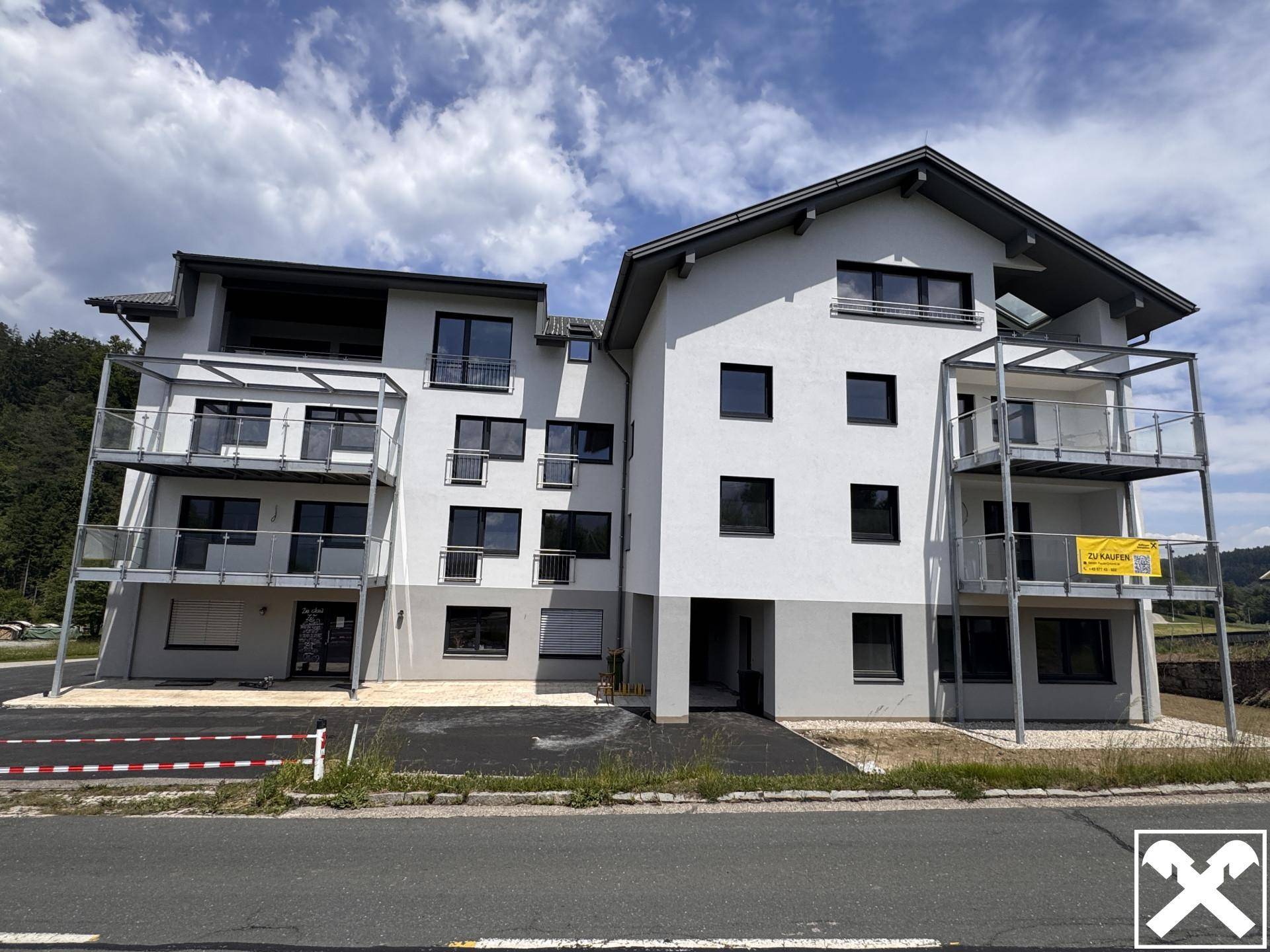 Frontansicht eines modernen Apartmentgebäudes mit mehreren Balkonen und klaren Linien.