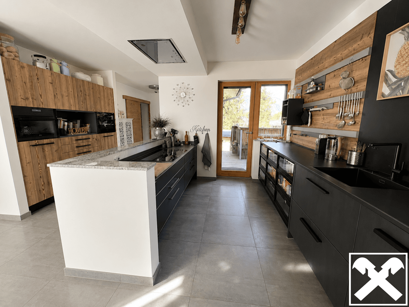 Moderne Küche mit Kücheninsel, Holz- und Anthrazitfronten sowie Zugang zum Balkon.