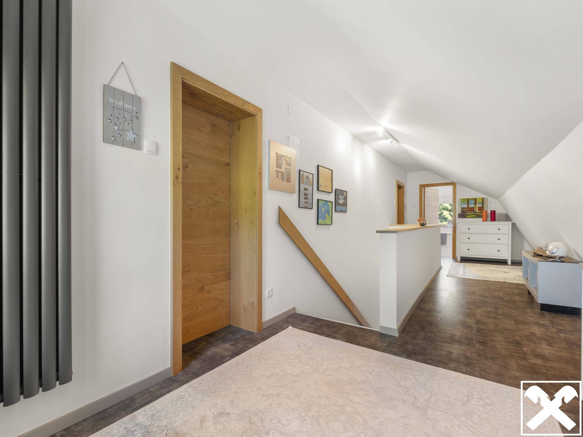 Heller Flur im Dachgeschoss mit Dachschrägen, Holztüren und modernem Heizkörper.