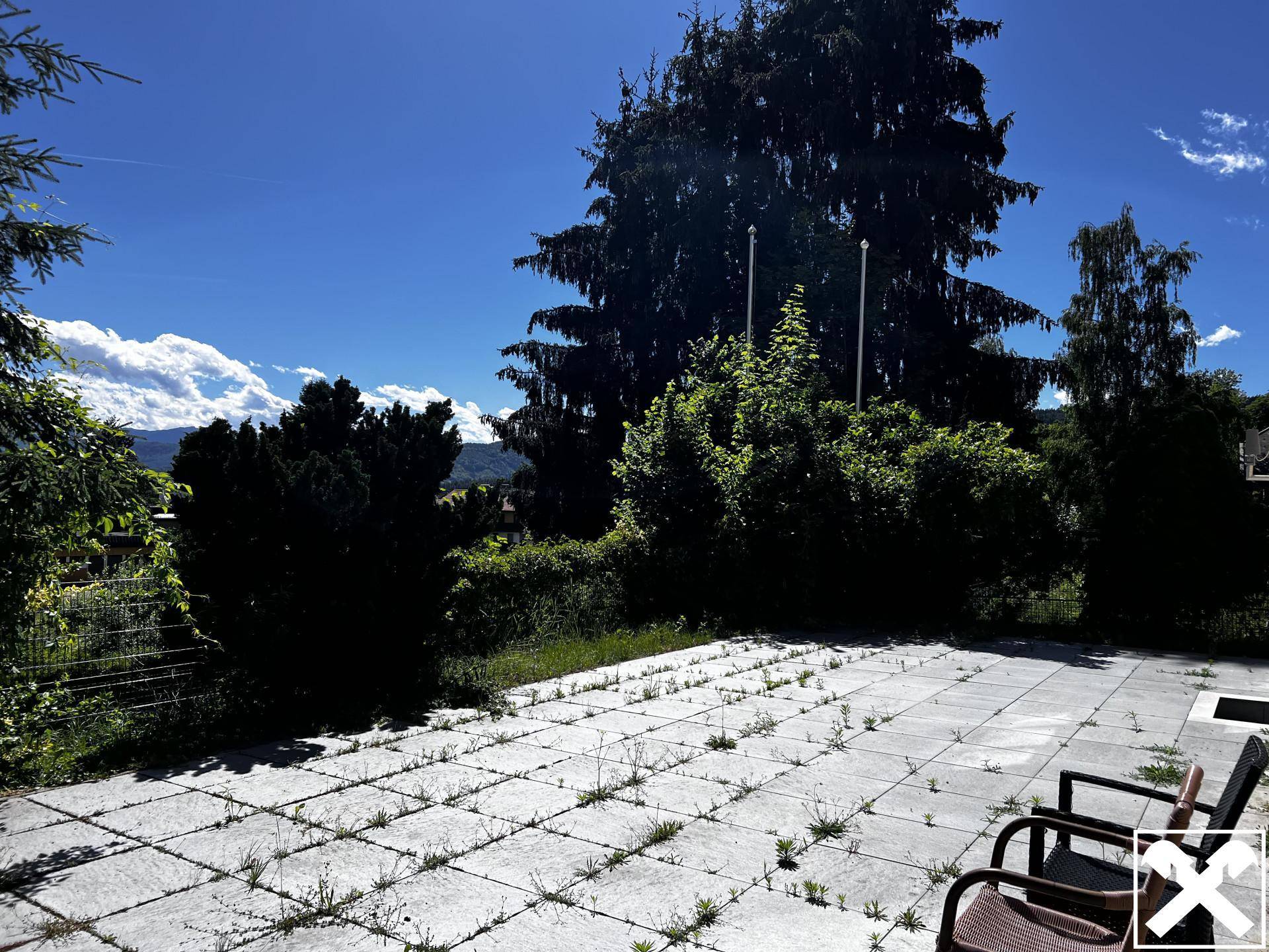 Große, gepflasterte Terrasse im Gartenbereich mit Sitzgelegenheiten und Blick ins Grüne.