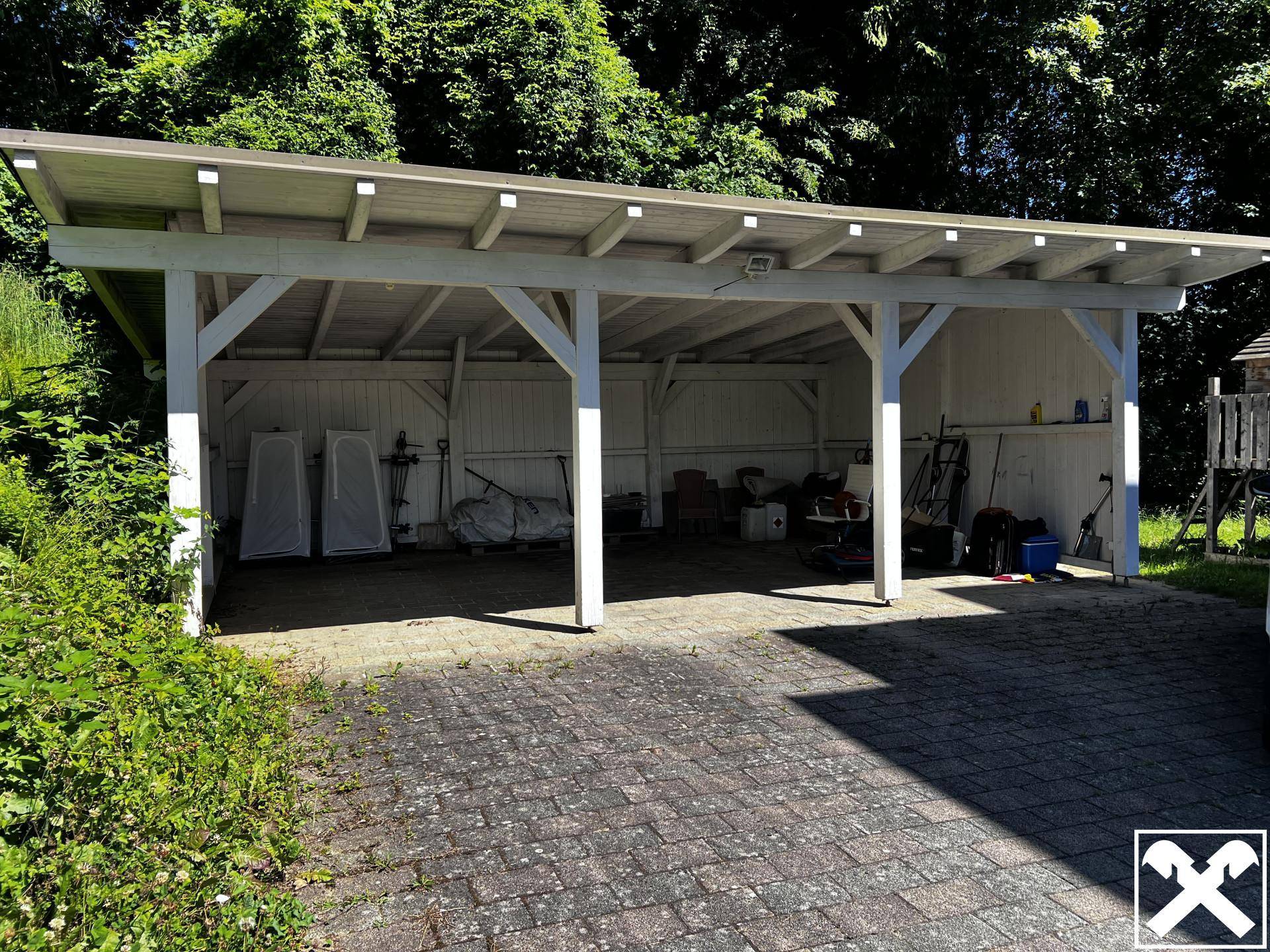 Geräumiger Holz-Carport mit mehreren Stellplätzen und Abstellmöglichkeiten im Freien.