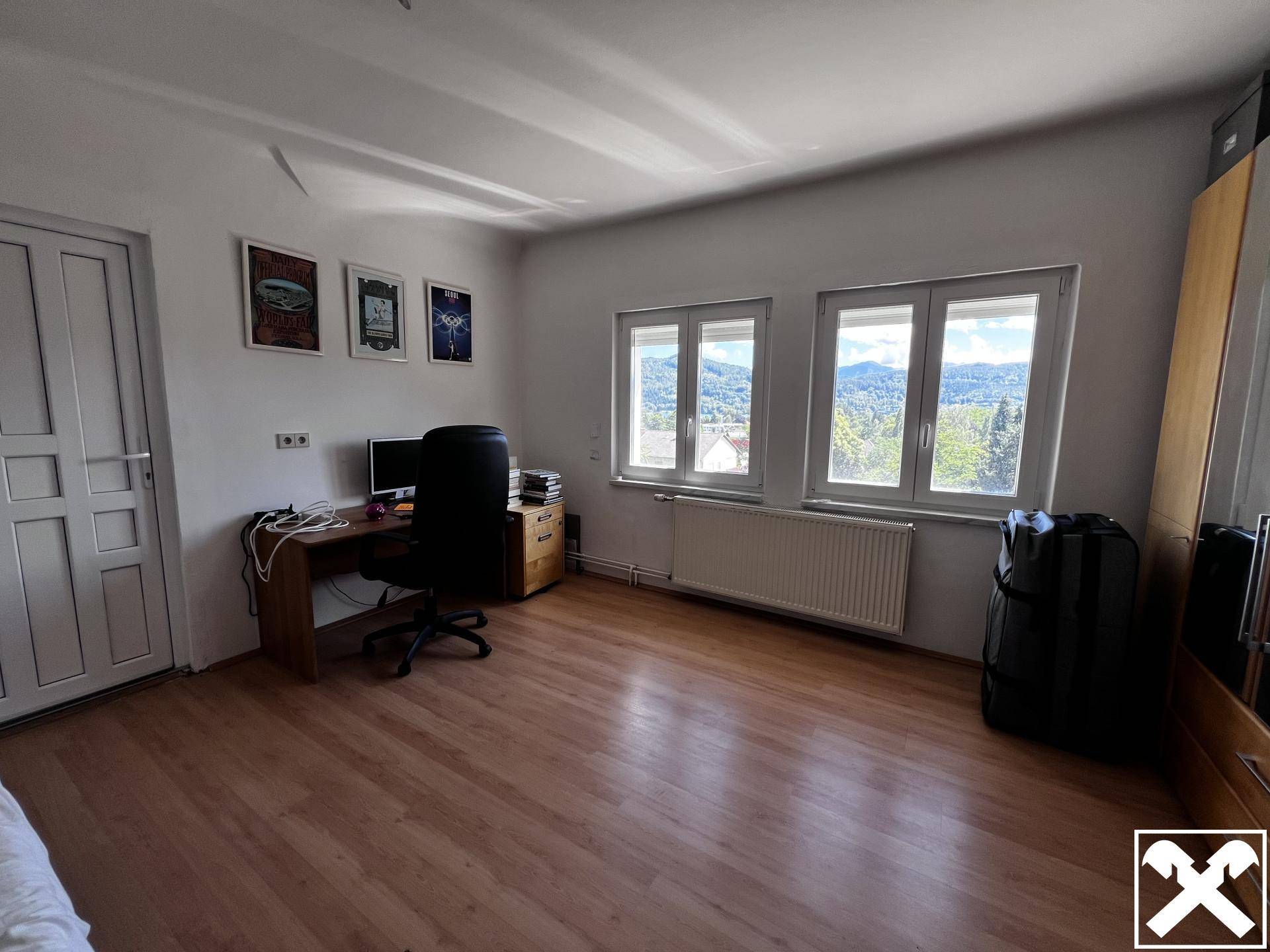 Geräumiges Zimmer mit Laminatboden, Schreibtisch und Fenstern mit Bergblick.