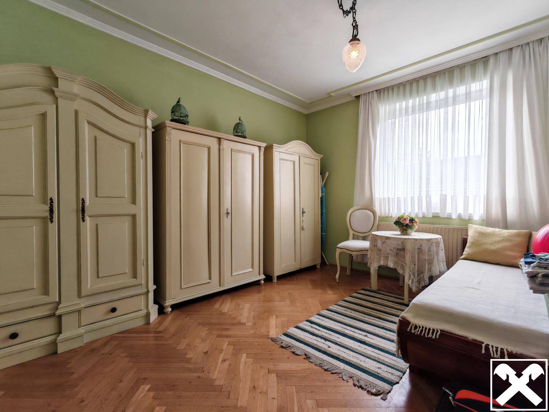 Gemütliches Schlafzimmer mit Holzparkett, grünen Wänden und traditionellen Holzschränken.