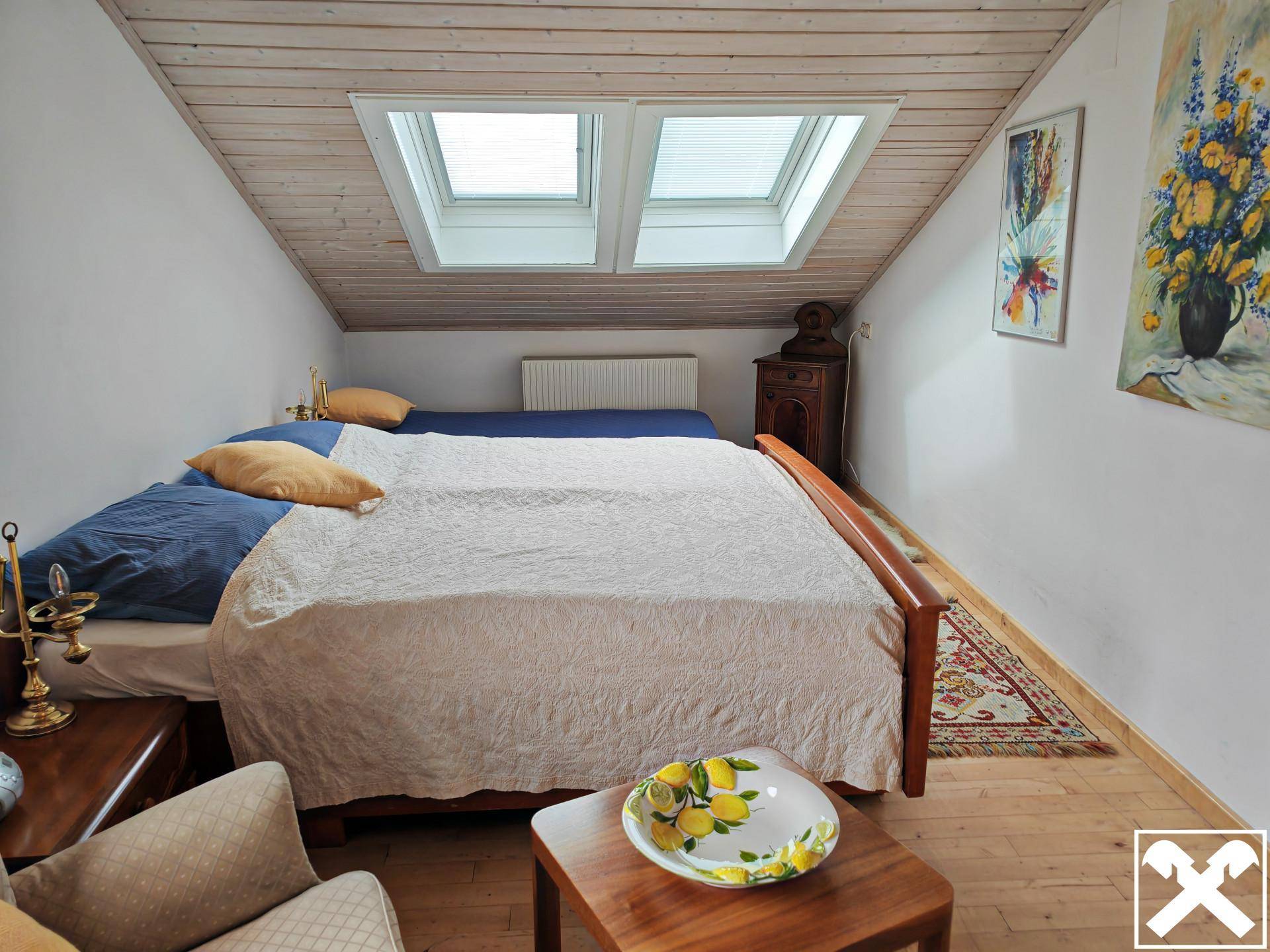 Gemütliches Schlafzimmer im Dachgeschoss mit Holzdecke, Holzboden und Dachfenstern.