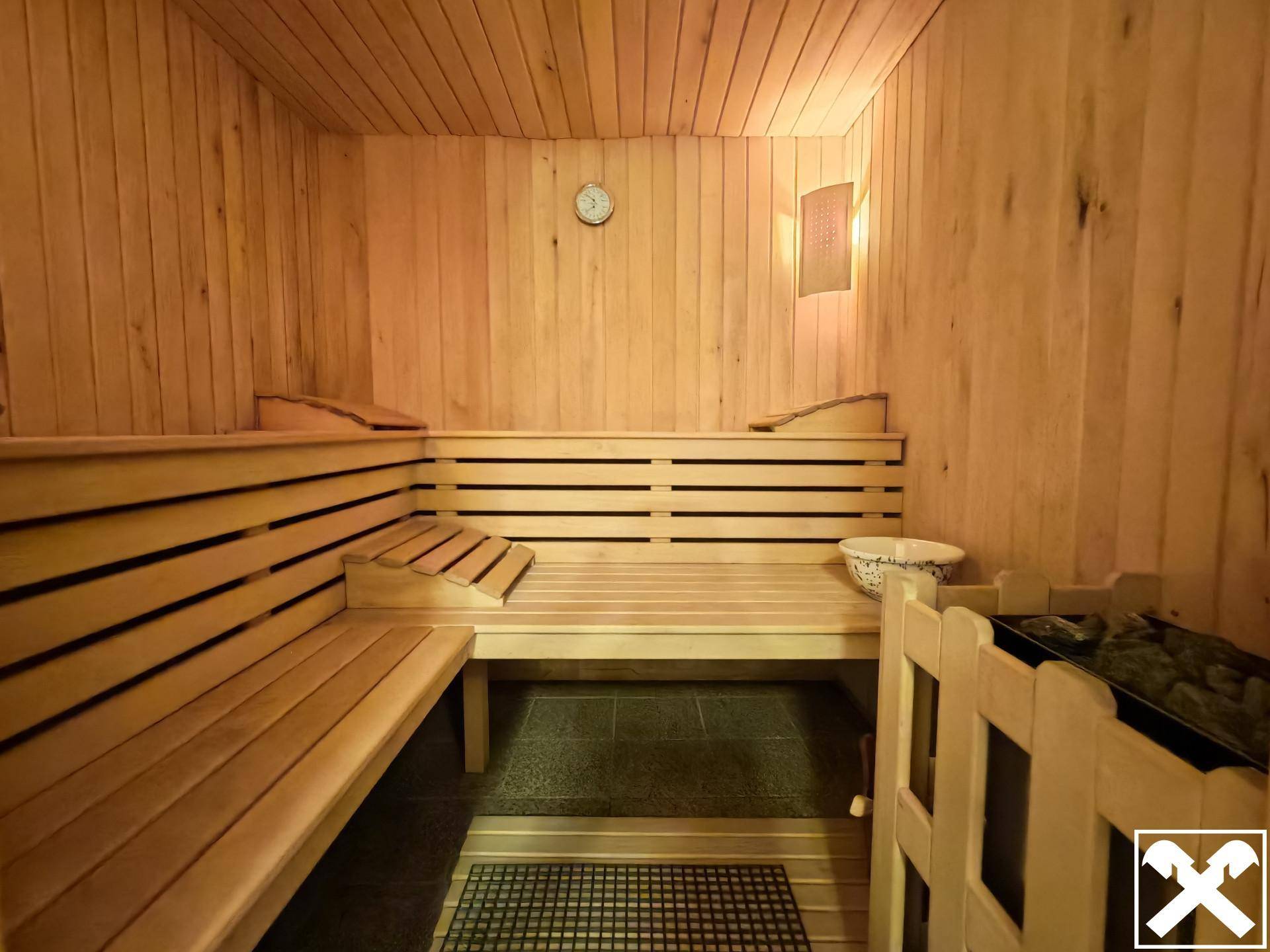Helle Holzsauna mit mehreren Bänken und traditionellem Saunaofen für Entspannung und Wellness.