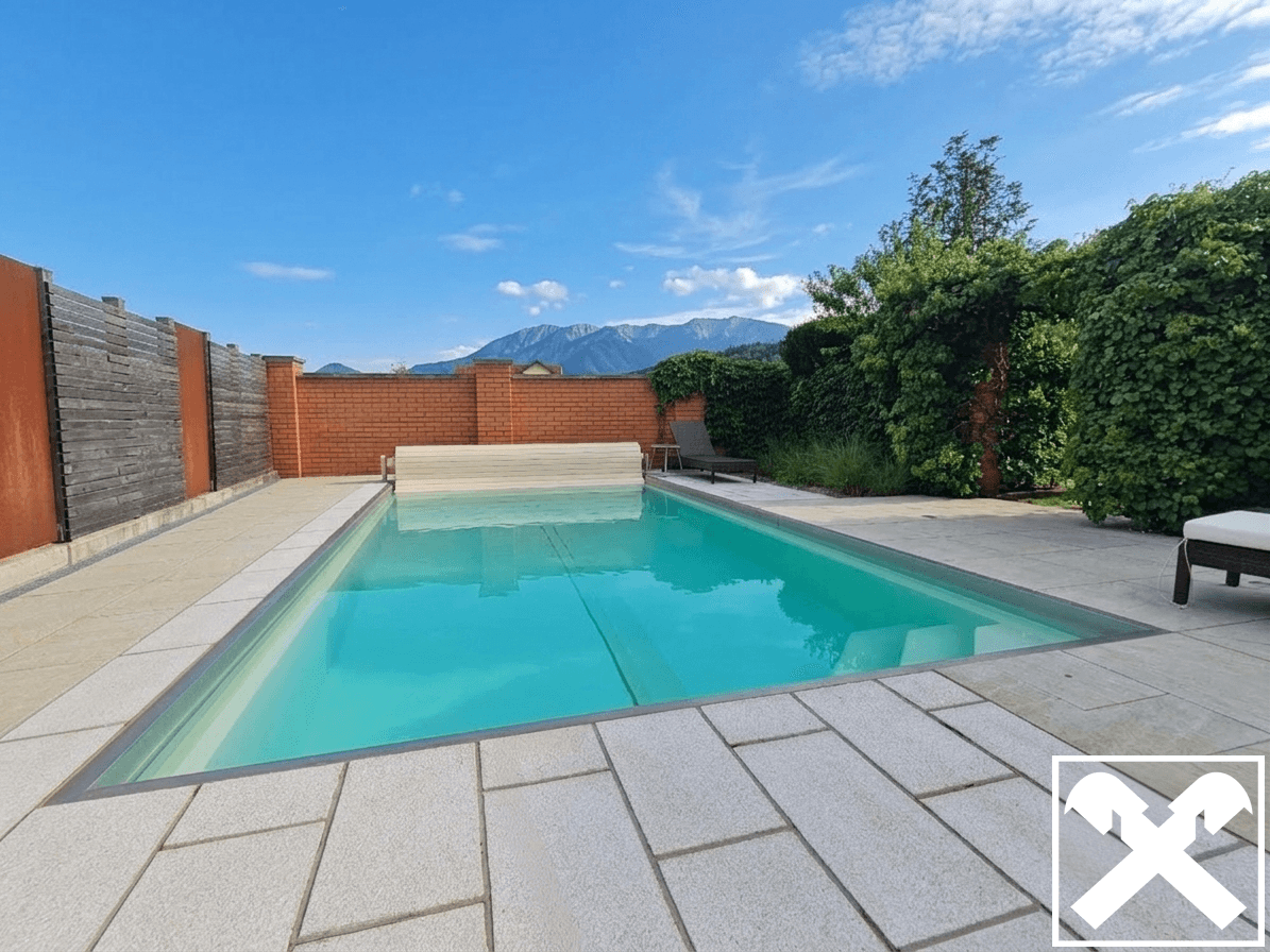 Privater Swimmingpool mit gepflasterter Sonnenterrasse und herrlichem Bergblick im Hintergrund.