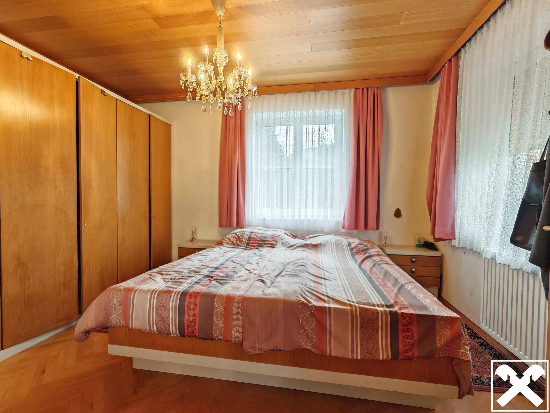 Schlafzimmer mit Holzdecke, Parkettboden, großem Bett und Einbauschränken.