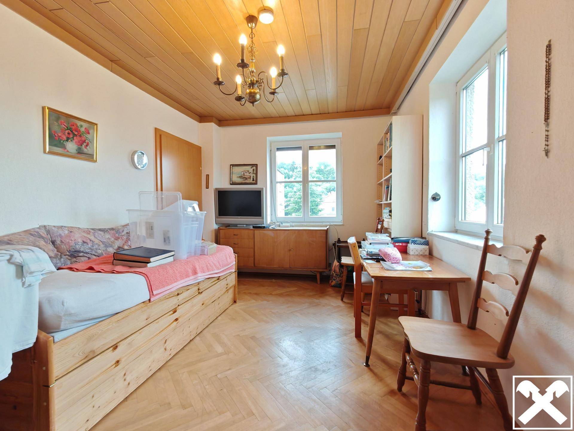 Helles Zimmer mit Holzdecke, Parkettboden und Fenster, ideal als Schlaf- oder Arbeitszimmer.