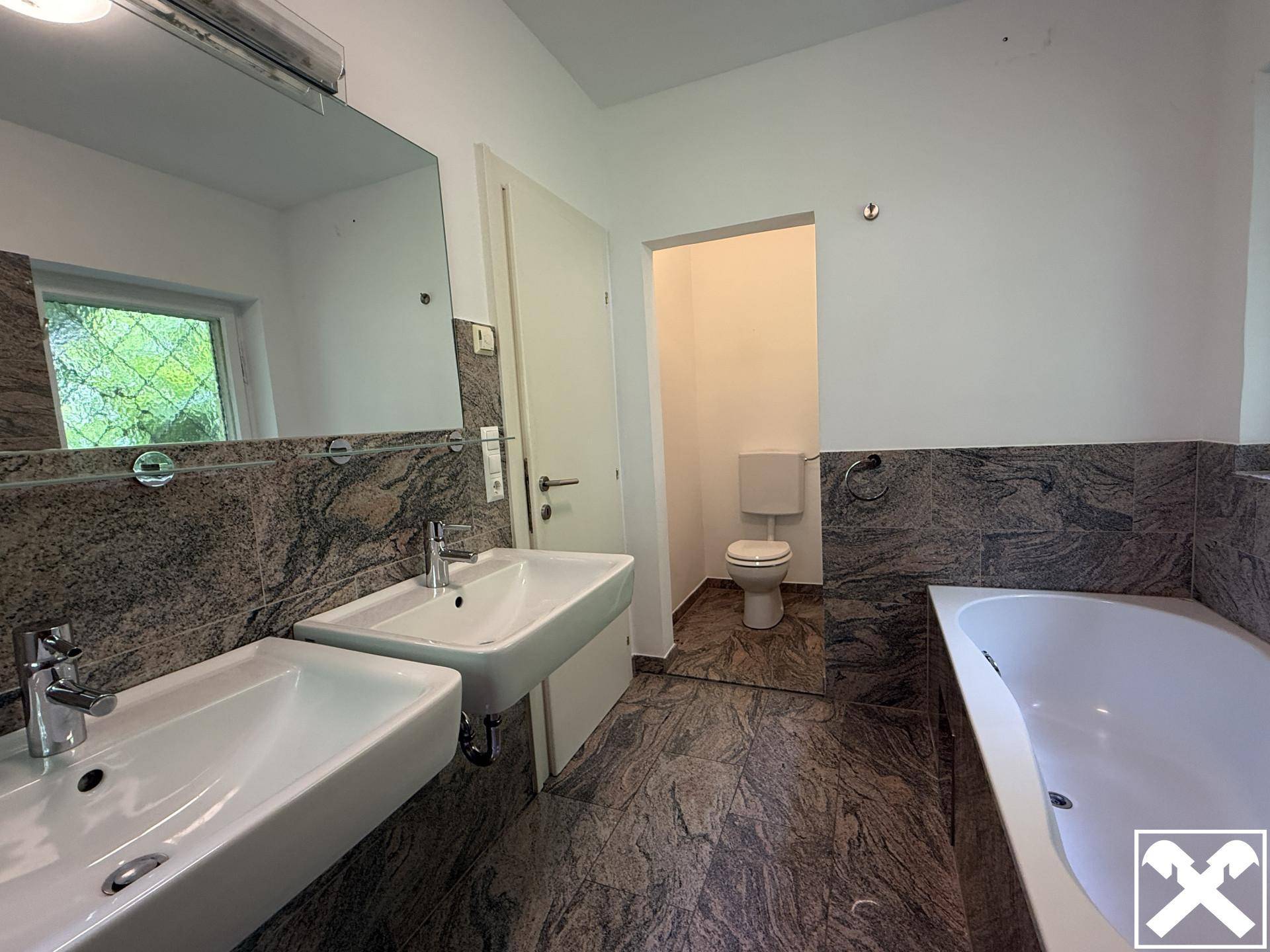 Geräumiges Badezimmer mit Doppelwaschbecken, Granitfliesen und separatem WC-Bereich.