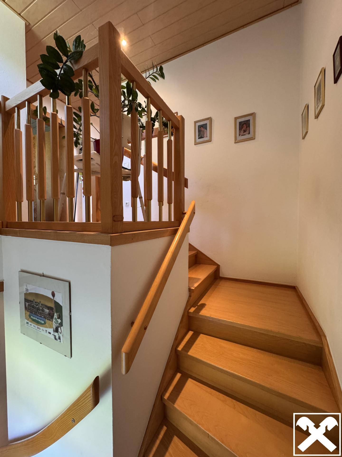 Holztreppe mit Geländer, die die verschiedenen Etagen des Hauses miteinander verbindet.