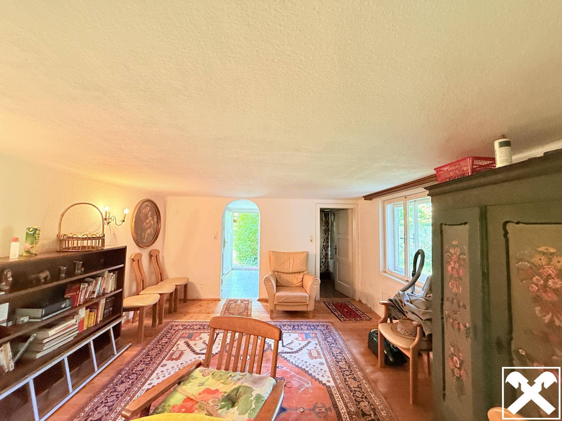 Gemütliches Wohnzimmer mit traditionellen Holzmöbeln, Teppich und Blick ins Grüne.