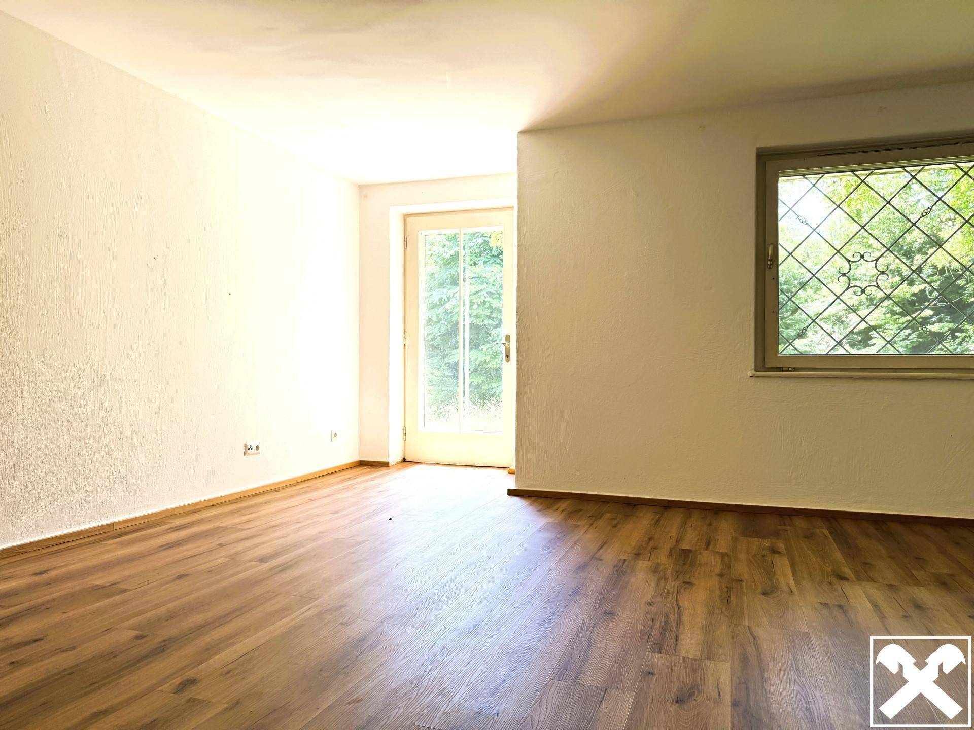 Helles Zimmer mit Laminatboden und großem Fenster, ideal als Schlaf- oder Arbeitszimmer.