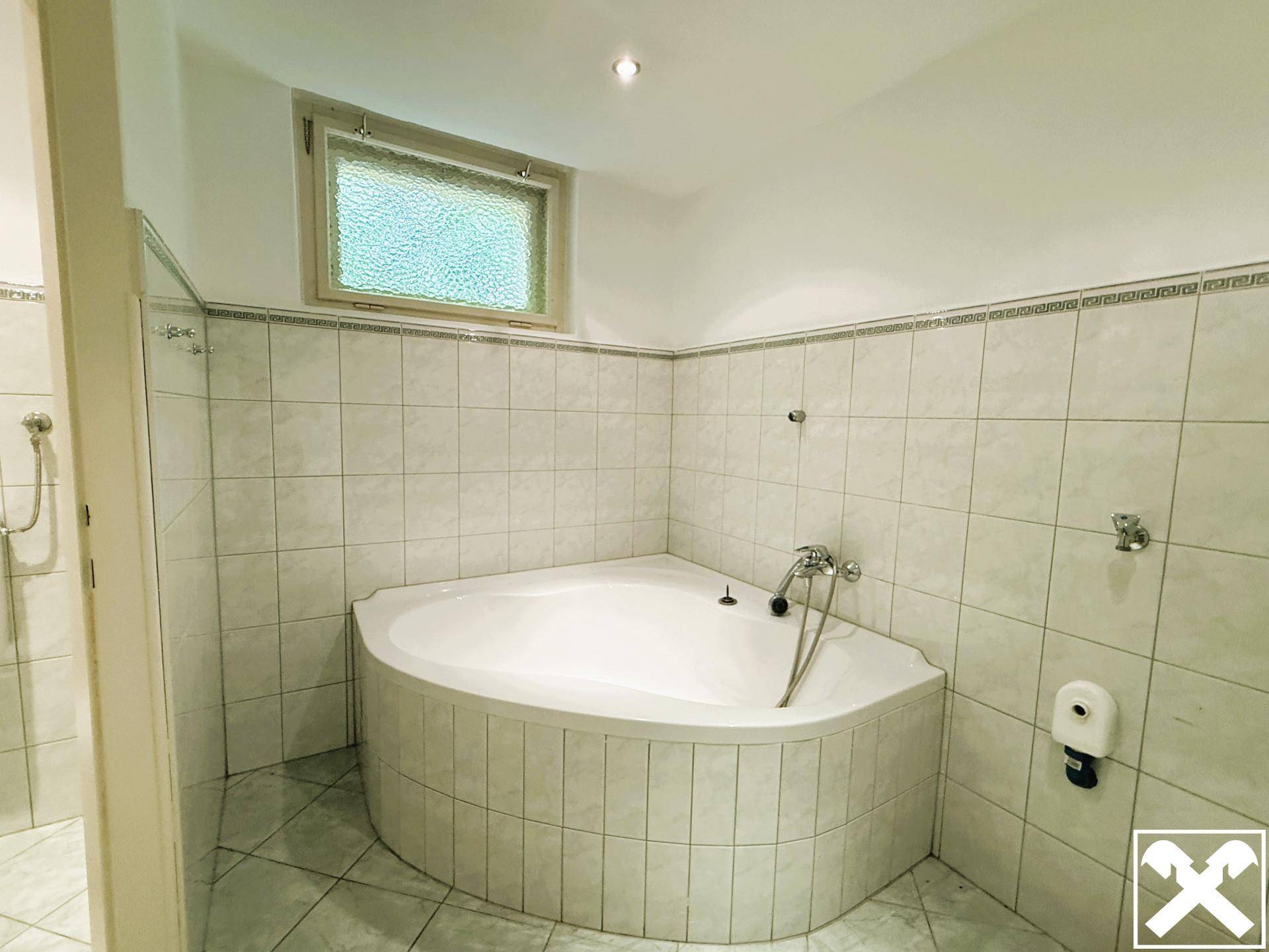 Badezimmer mit großer Eckbadewanne und hellen Fliesen, bereit zur individuellen Gestaltung.