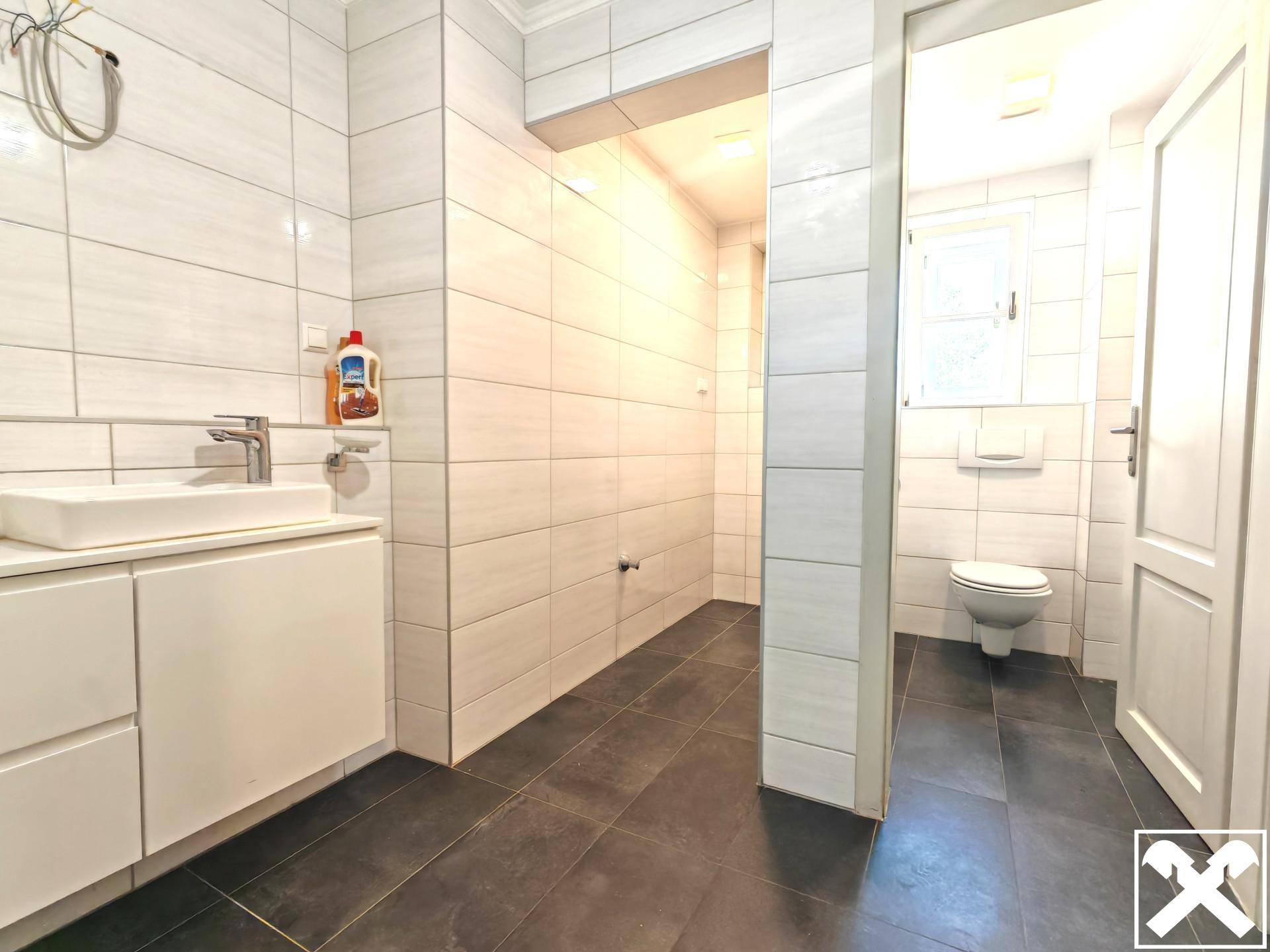 Helles Badezimmer mit modernem Waschtisch und Zugang zu einem separaten WC-Bereich.