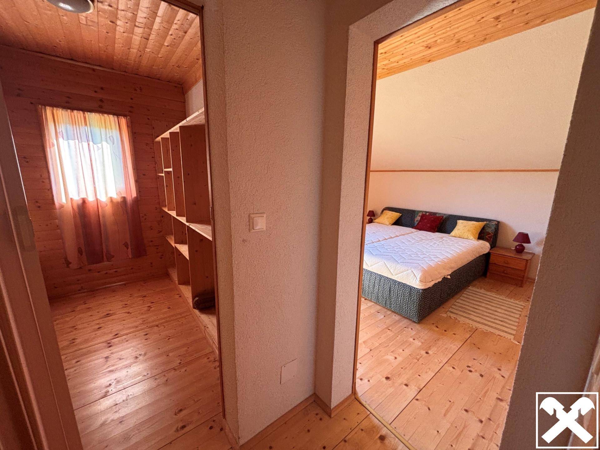 Schlafzimmer mit Holzboden und Zugang zu einem begehbaren Kleiderschrank mit Regalen.