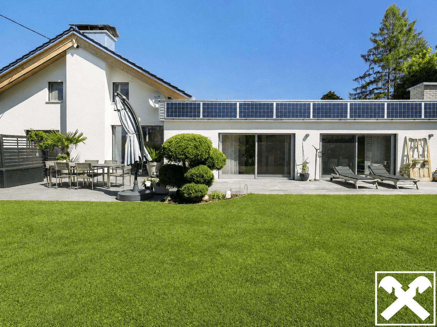 Große Sonnenterrasse mit Gartenmöbeln und Liegestühlen, umgeben von einem gepflegten Rasen.
