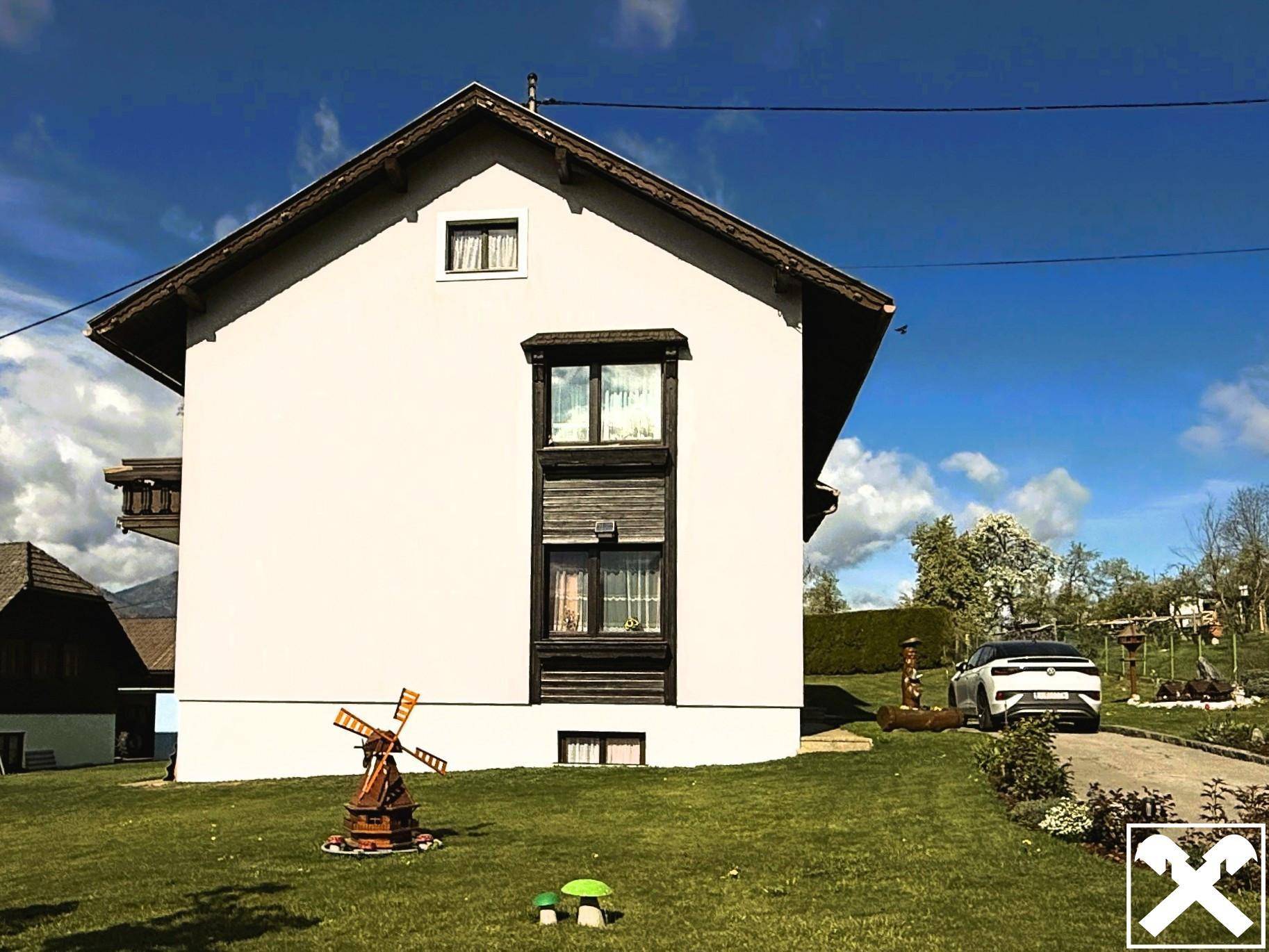 Seitenansicht des Hauses mit gepflegtem Rasen und dekorativer Windmühle im Vorgarten.