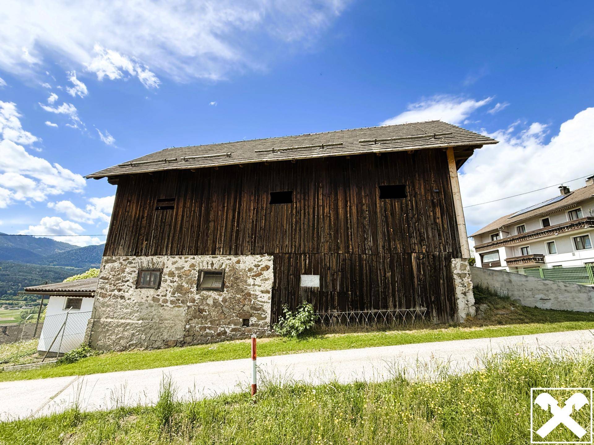 Rustikales Holzgebäude mit Steinfundament und traditioneller Bauweise in ländlicher Umgebung.