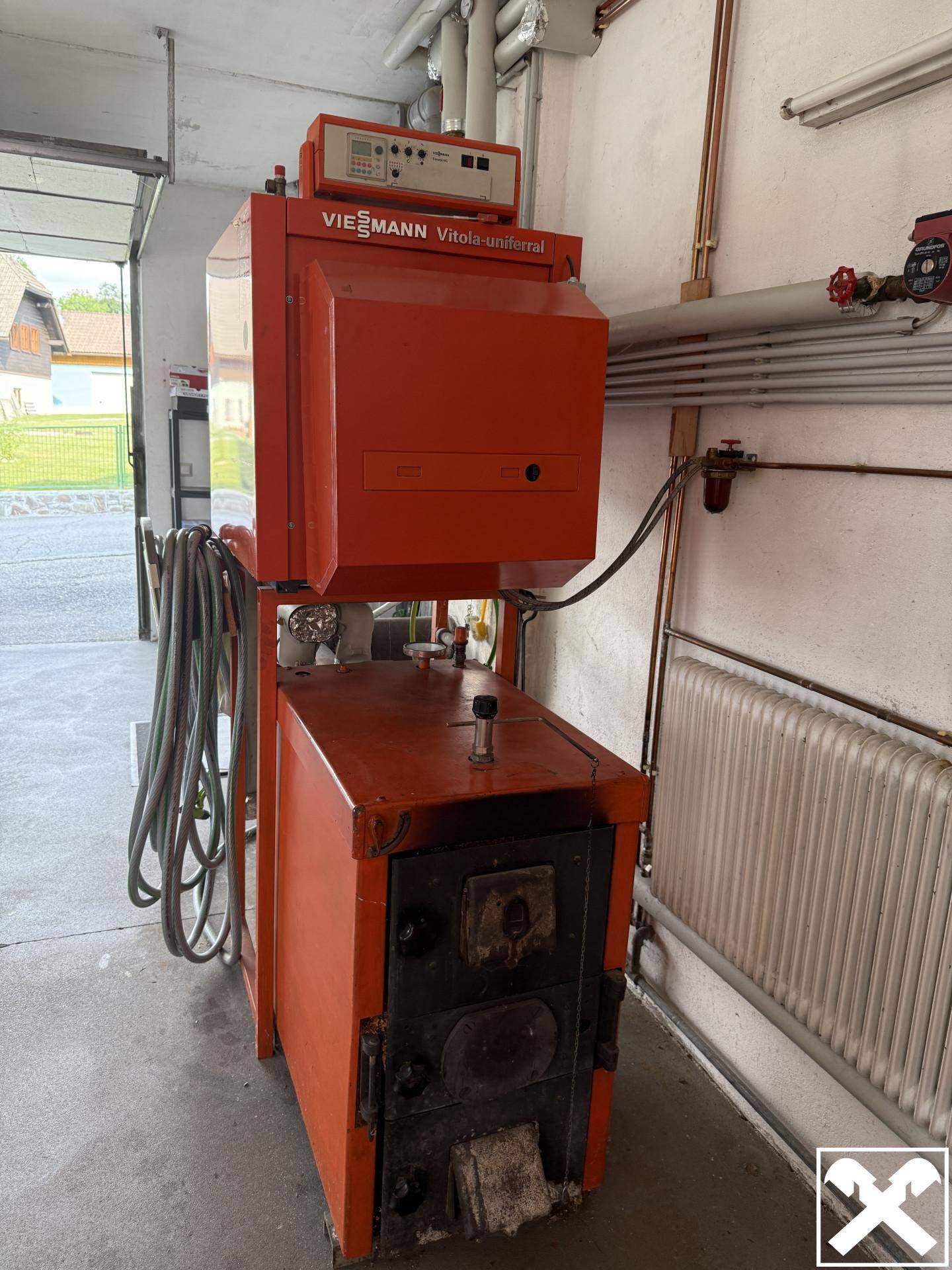Detailansicht der Heizungsanlage in einem Technikraum oder der Garage, mit Rohren und Heizkessel.