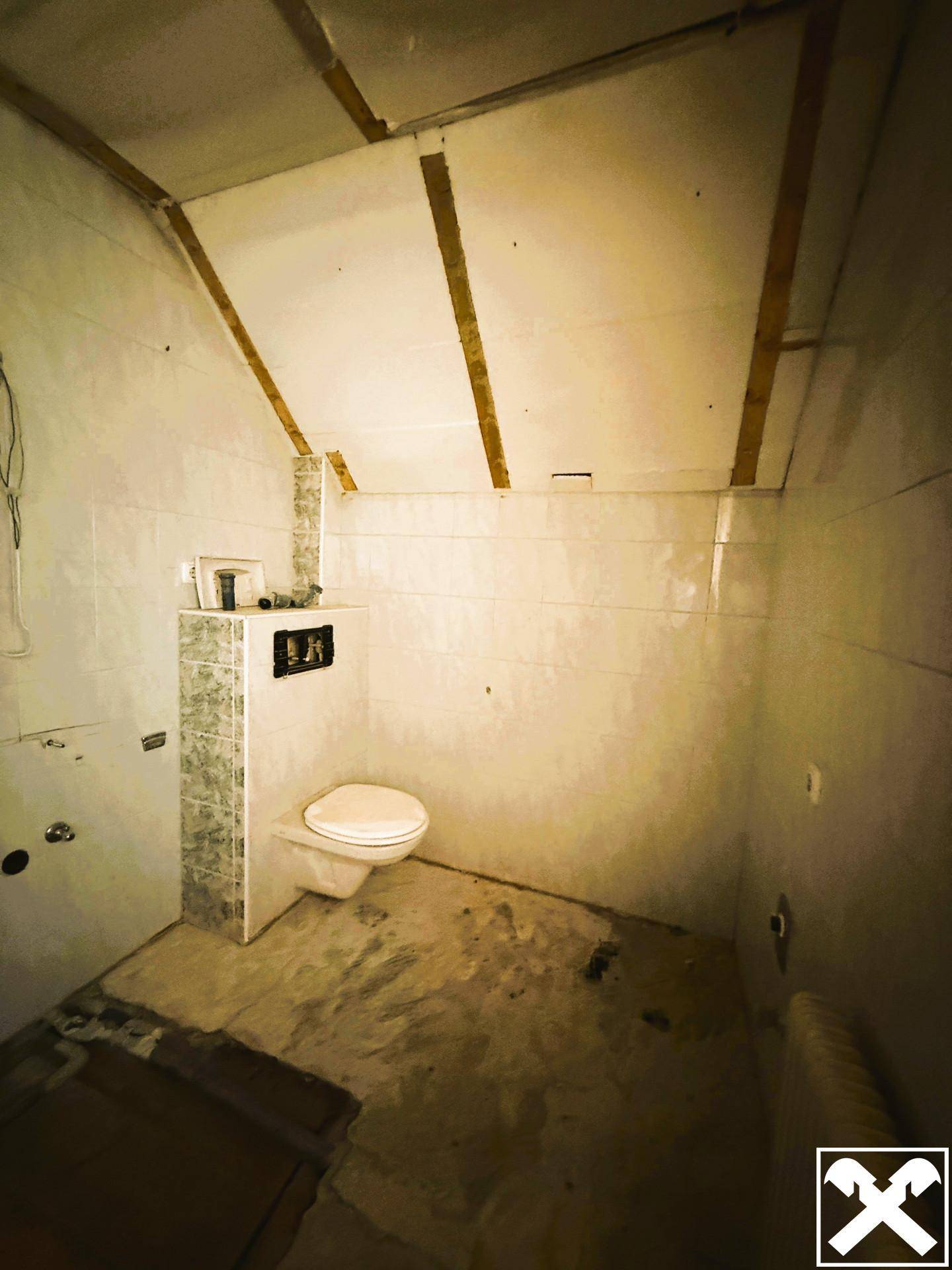 Renovierungsbedürftiges WC mit Wand-WC und Fliesen, bereit für die Fertigstellung.