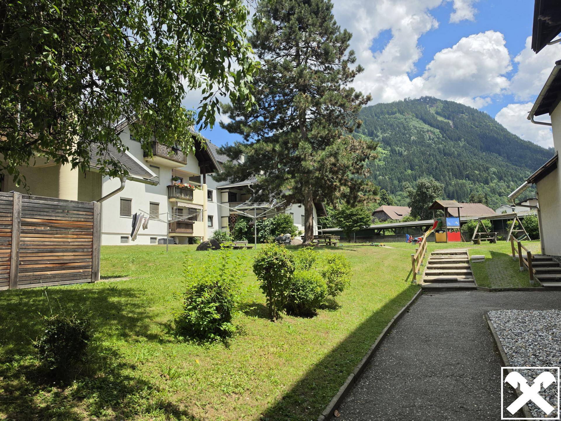 Außenansicht einer Wohnanlage mit großem Gemeinschaftsgarten und altem Baumbestand.