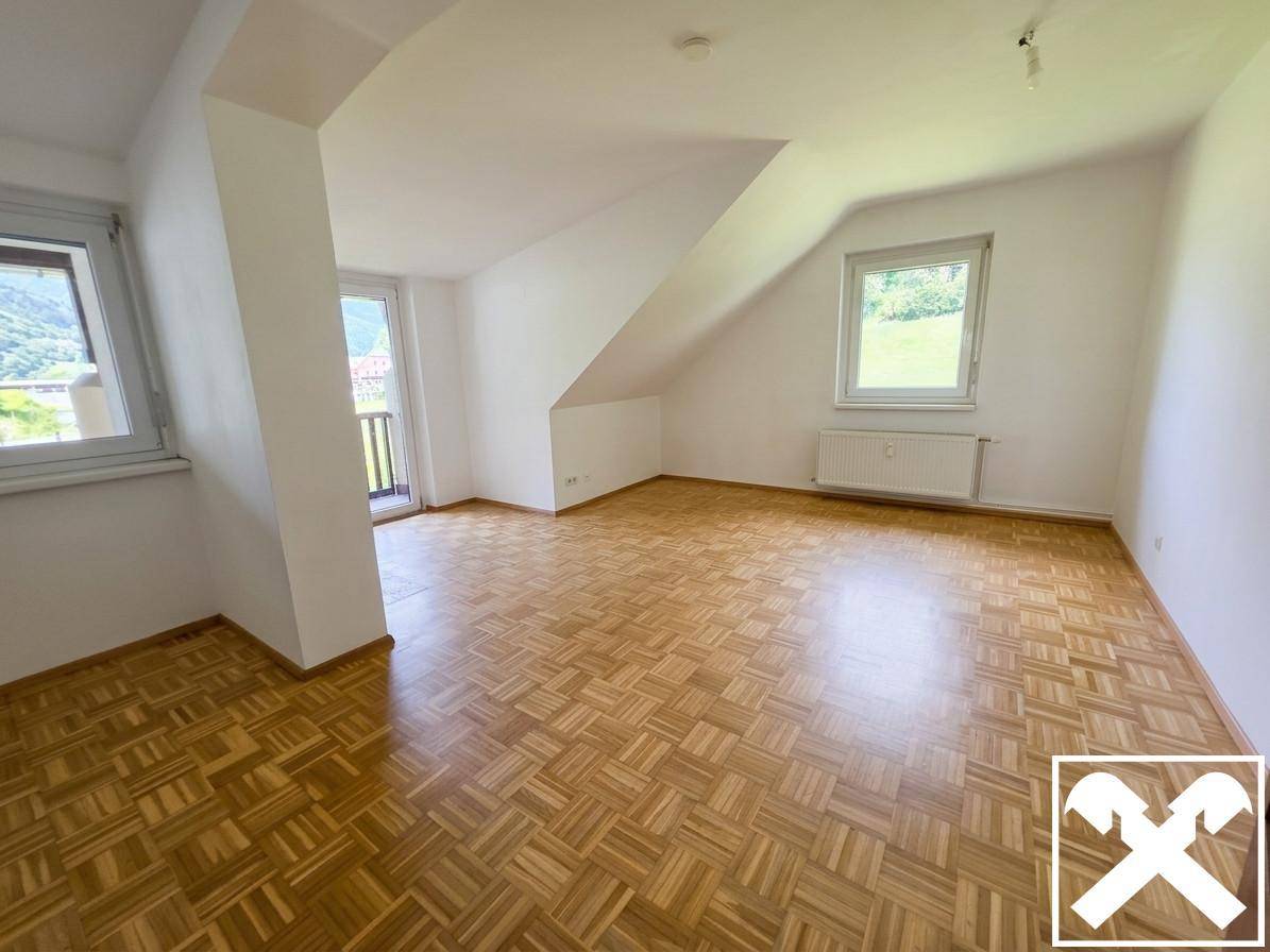 Heller Raum mit Parkettboden, Dachschrägen und Zugang zu einem Balkon mit Bergblick.