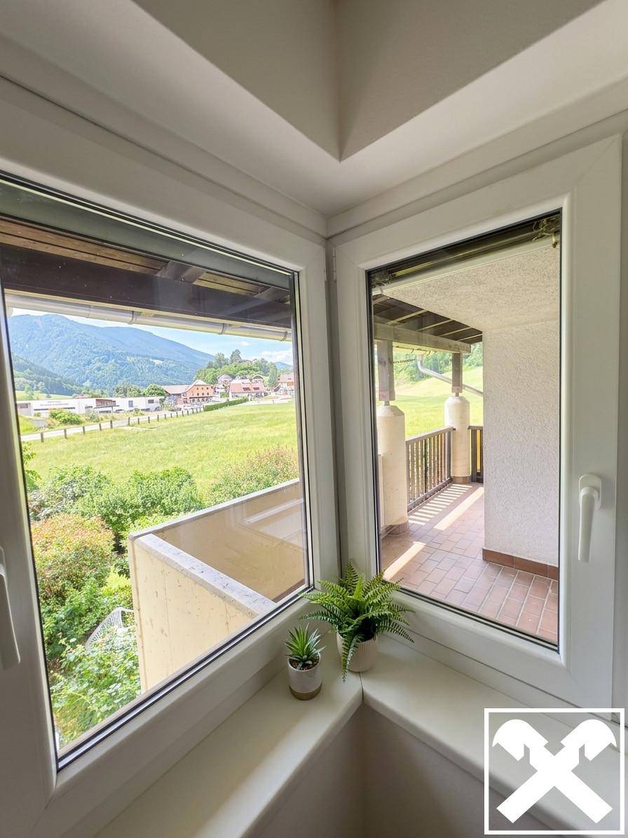 Blick aus einem Fenster auf einen Balkon und die malerische Berglandschaft.