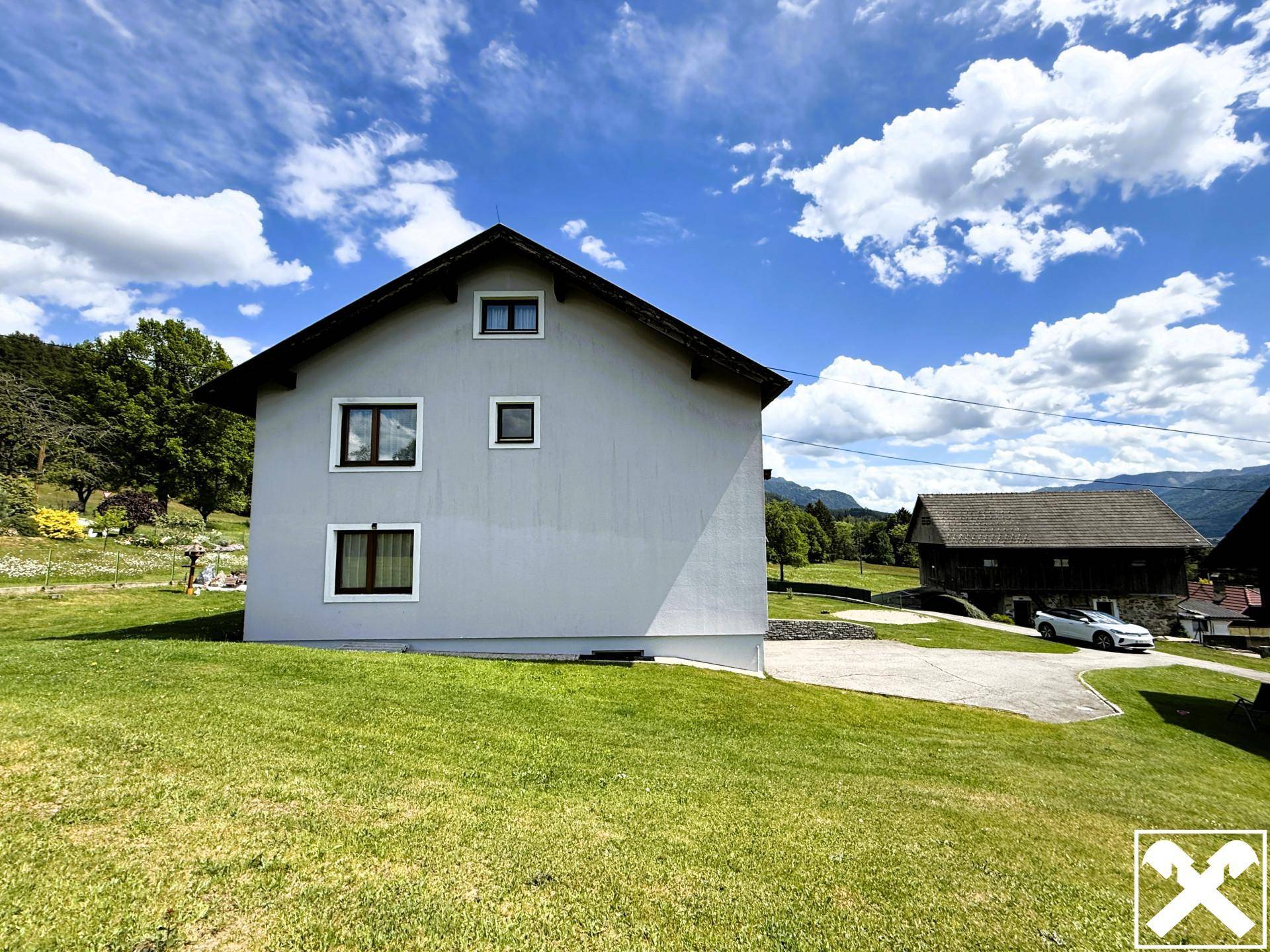 Rückseite des Hauses mit weitem Blick über die grüne Landschaft und die Berge.