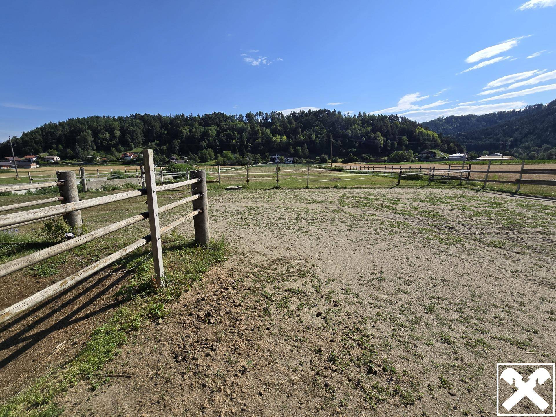 Weitläufiges, eingezäuntes Feld oder Paddock mit Blick auf die bewaldeten Hügel.