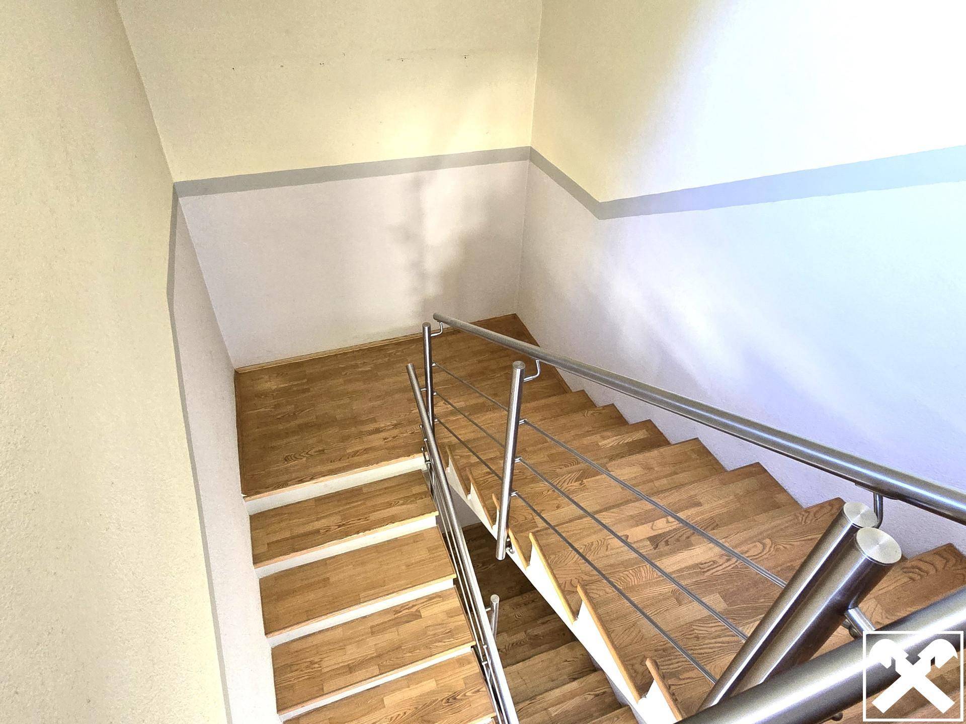 Holztreppe mit modernem Edelstahlgeländer, die die Stockwerke des Hauses verbindet.